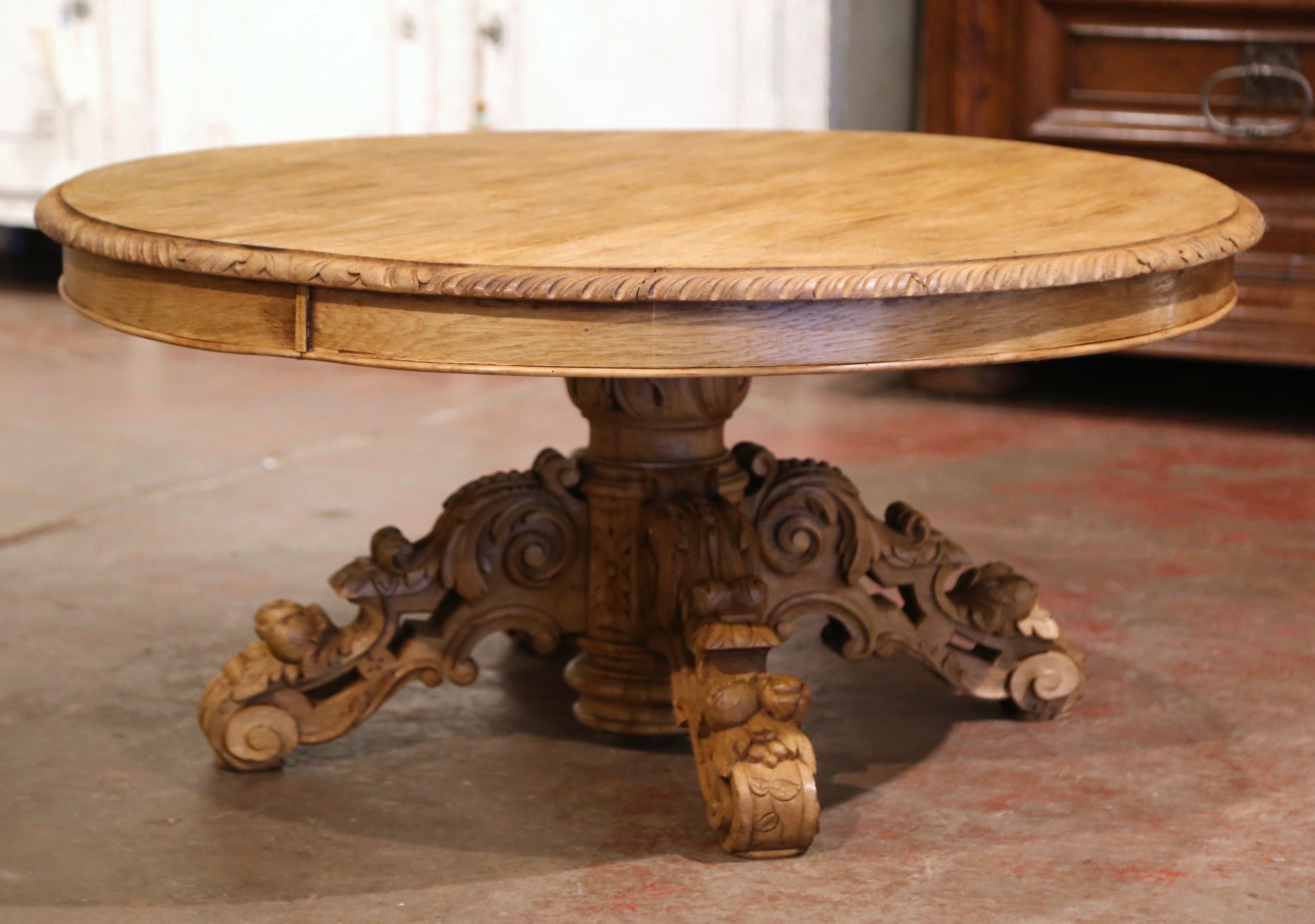 Crafted in northern France circa 1860 and almost round in shape, the antique coffee table stands on an elegant pedestal base dressed with hand carved acanthus leaves, over four legs decorated with fruit motifs. The sturdy Louis XIII style cocktail