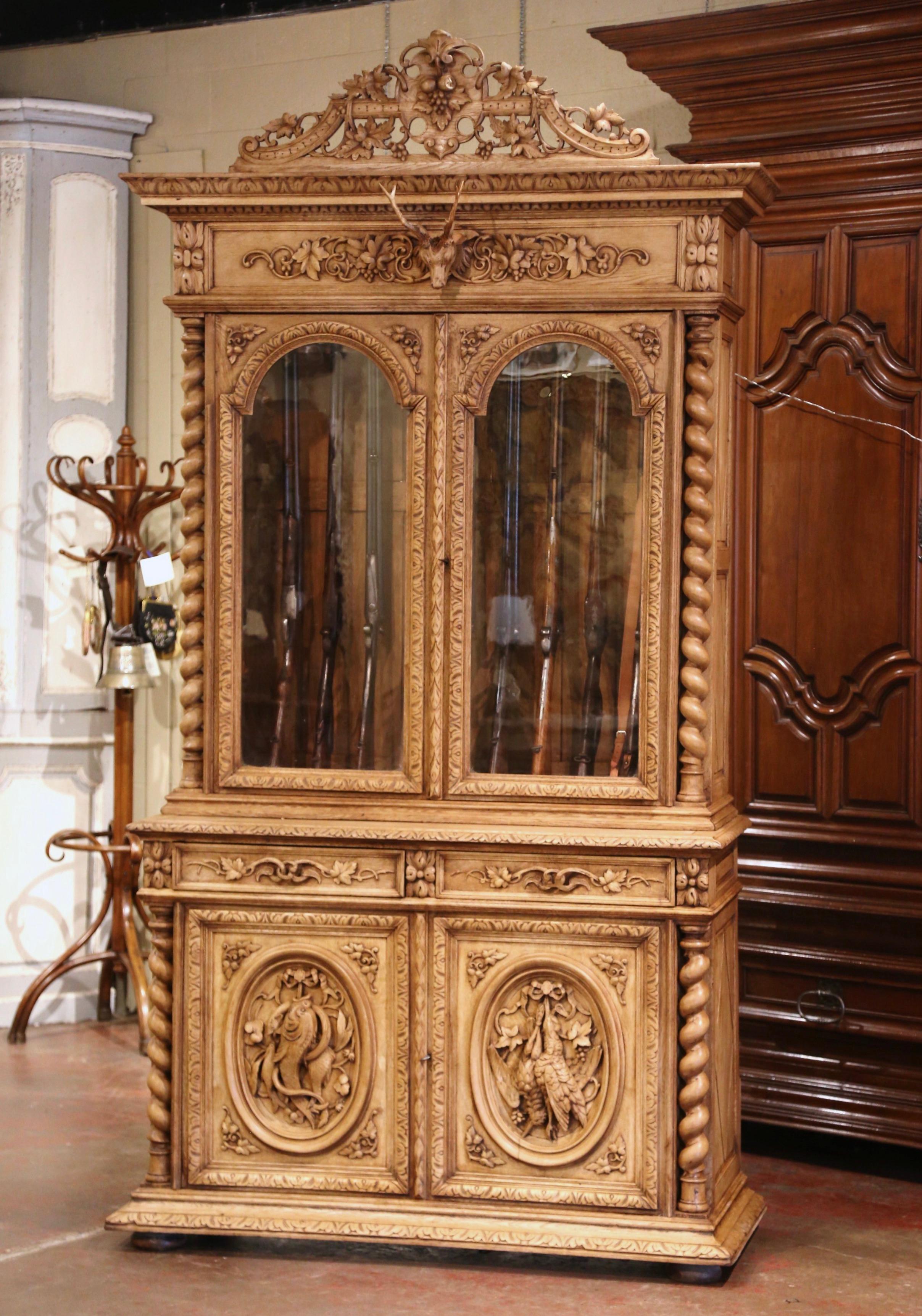 Display your rifle or shotgun collection in this beautifully carved, antique gun cabinet. Created in France, circa 1860, the two-piece buffet with barley twist side columns, sits on bun feet over a straight base plinth. The upper section decorated