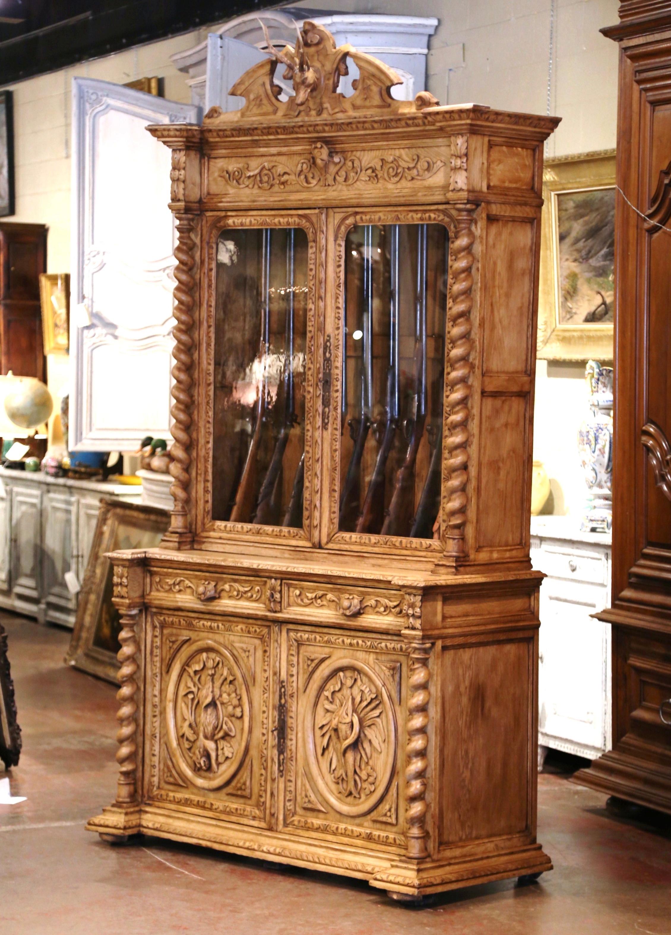 Display your rifle or shotgun collection in this beautifully carved, antique gun cabinet. Created in France, circa 1860, the two-piece buffet with barley twist side columns, sits on bun feet over a recessed base plinth. The upper section is