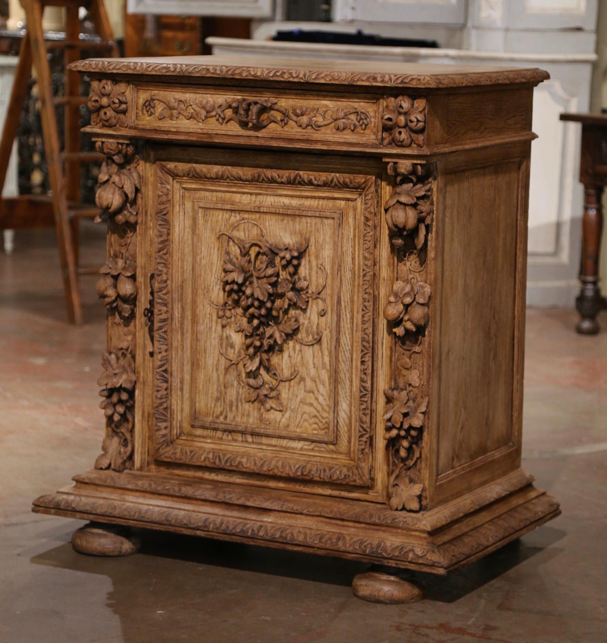 Decorate a wine cellar with this elegant and heavily carved antique cabinet. Crafted in France, circa 1870, the jelly cabinet stands on a wide and thick double molded plinth base over bun feet. The 
