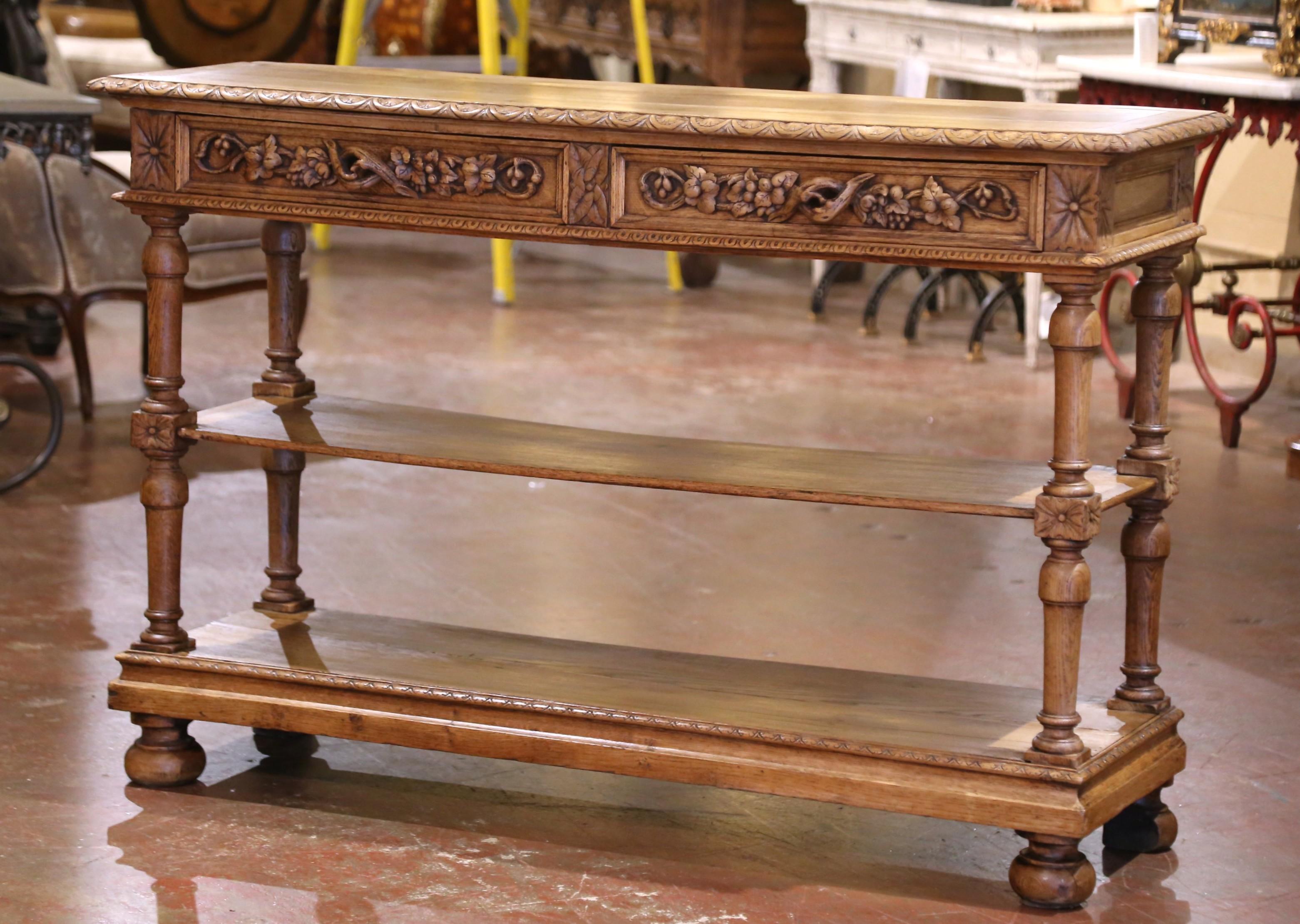 Dress a hallway, library, or living space with this elegant antique console table. Crafted in France circa 1870 and measuring nearly five feet in length, the tall, narrow server is built from richly light patinated oak with a warm, stripped