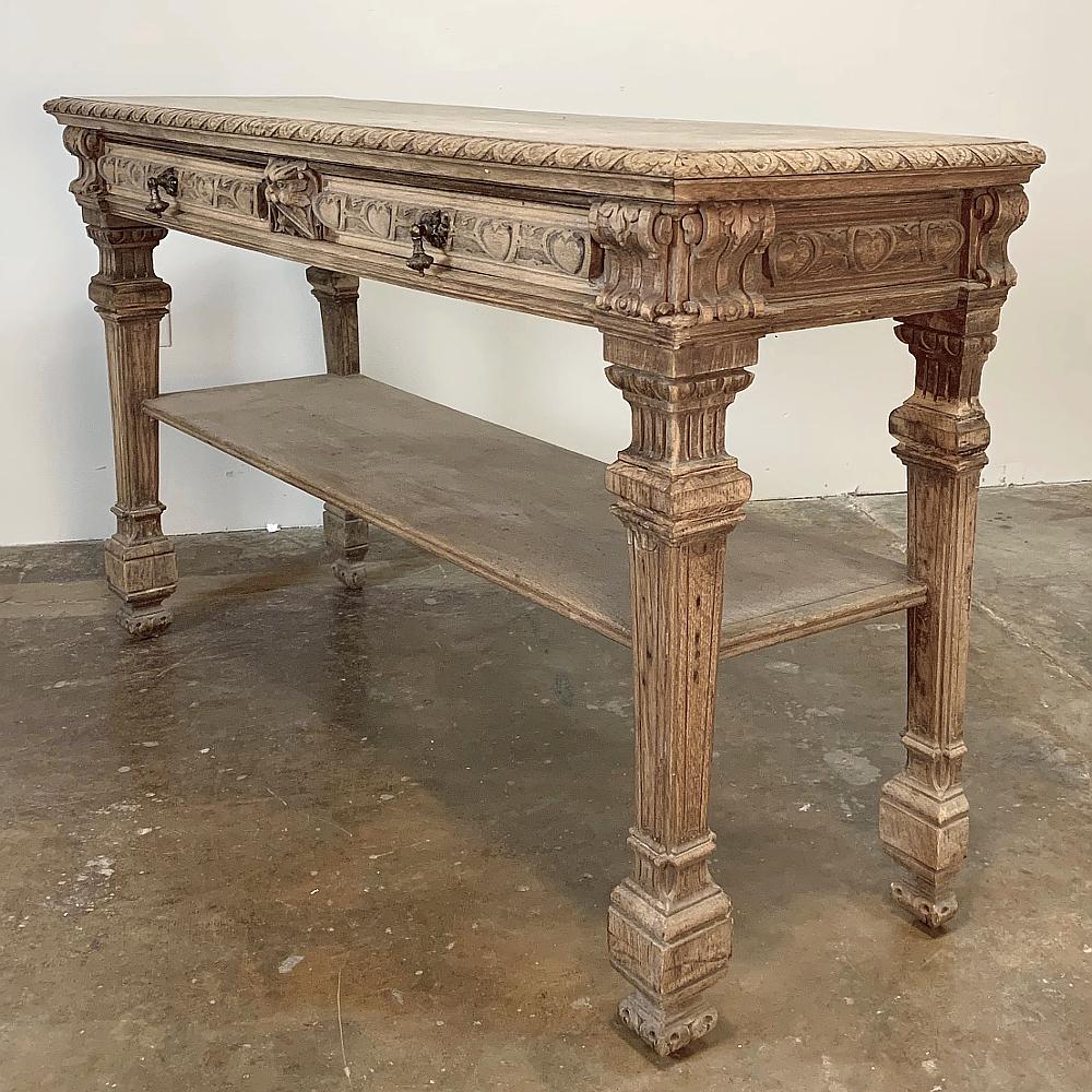 19th century French Henri II stripped console ~ sofa table is a handsome piece, with boldly carved relief across the upper tier depicting a Norseman flanked by detailed molding. Tapered and fluted legs add a neoclassical touch, and frame the lower