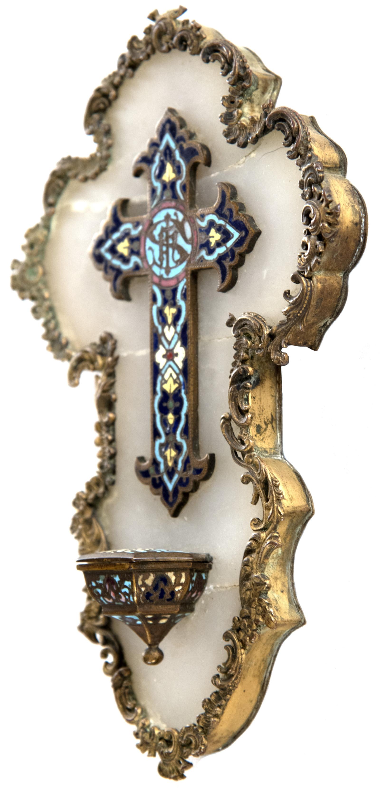 The hand painted enamel cross is decorated with a colourful motif in teal, rose, and yellow on a dark blue ground, the design further enhanced by its decorative form. The center stem is inlaid with the representation of the name of Jesus with the