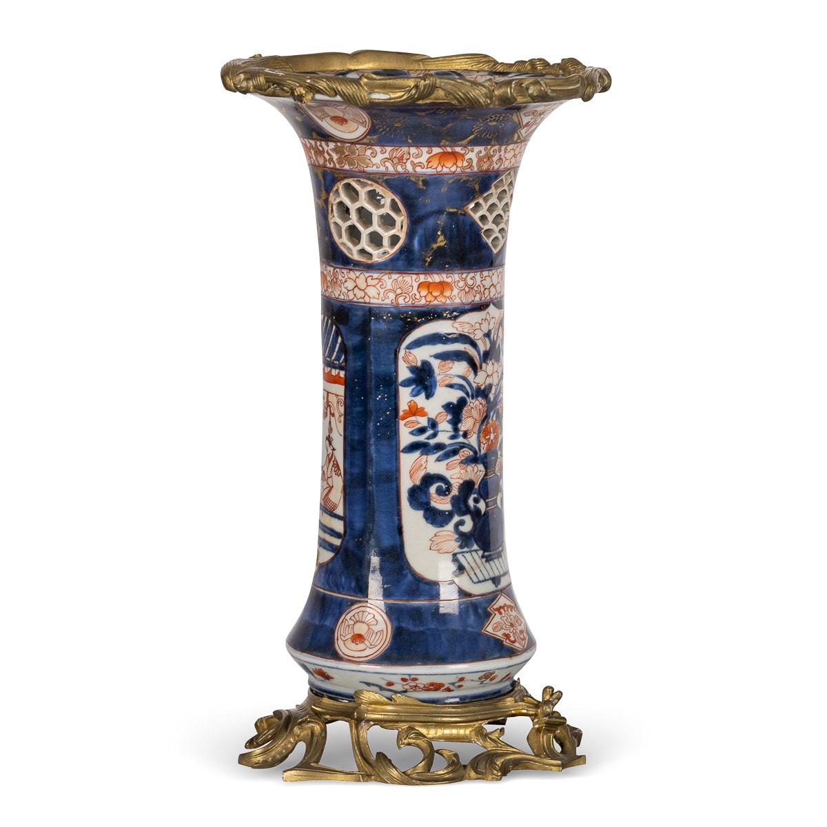 Antique late-19th century French Imari style porcelain vase mounted on ormolu. The cylindrical body fitted with a ormolu cast floral and scroll rim and raised on a pierced voluted ormolu base, vase decorated with traditional Japanese rural scenes