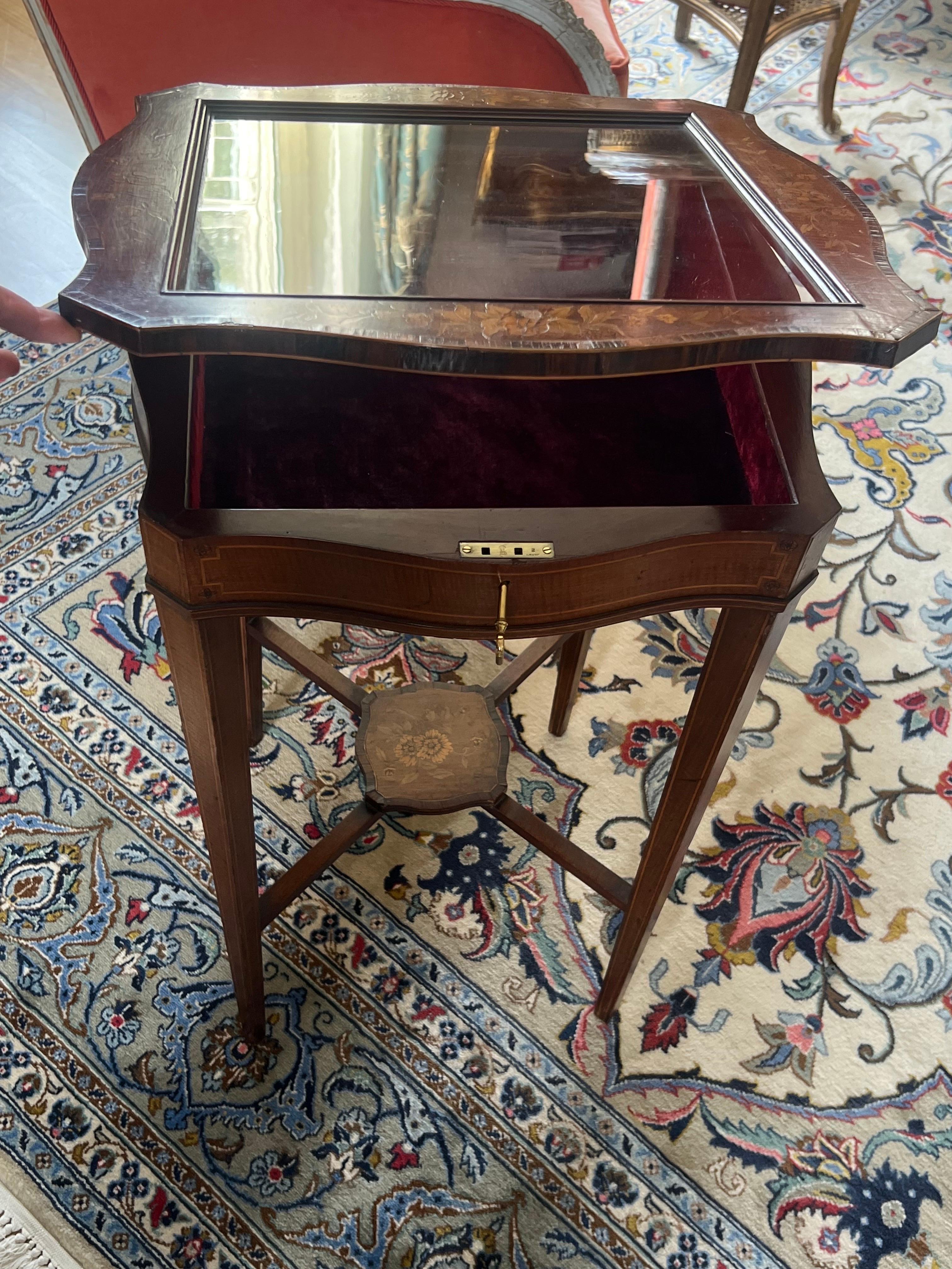 Fina joya francesa como la Mesa Vitrina de estilo Luis XV. Forma cuadrada con tapa abatible de cristal y tapicería de terciopelo. El cristal superior está rodeado de un marco incrustado y hay un pequeño segundo estante en la parte inferior de la