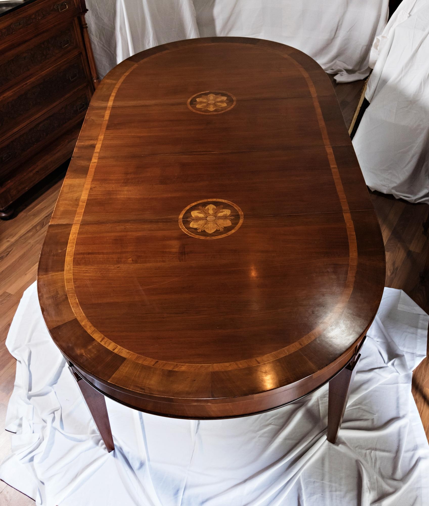 Late 19th century Louis XVI walnut inlay dining table. This gorgeous table has inlay trim encircling the top,  as well as two beautiful inlaid acorn rosettes when both leaves are in place. The table is 105.5 inches long with the two leaves and 67