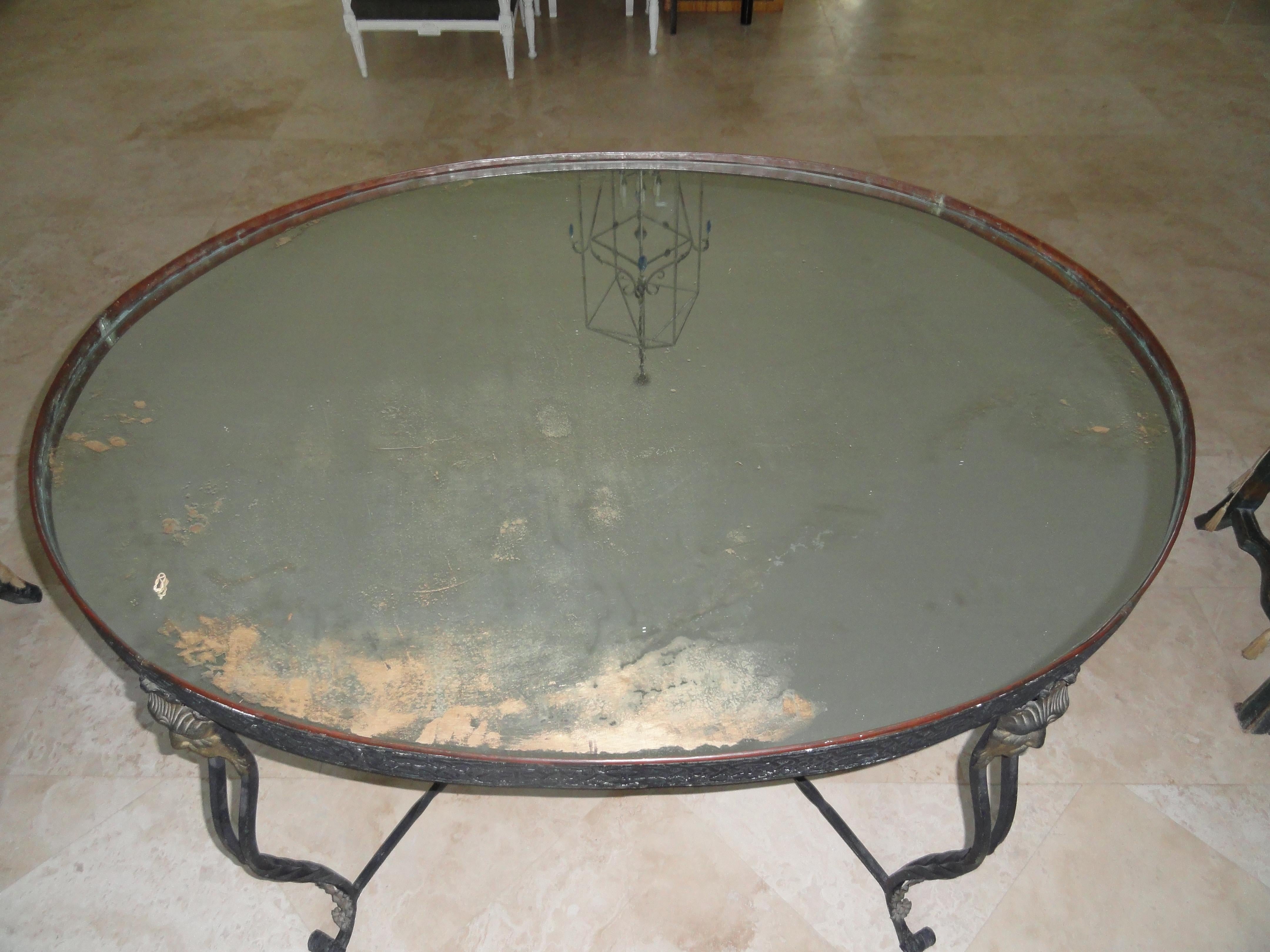 19th century French elliptical table with copper insert top. Four shaped metal legs terminating in metal masks. Shaped stretcher. Intricate apron detail. Inserted copper tray with mirrored inset.
A stunning example of French metal craft designed as