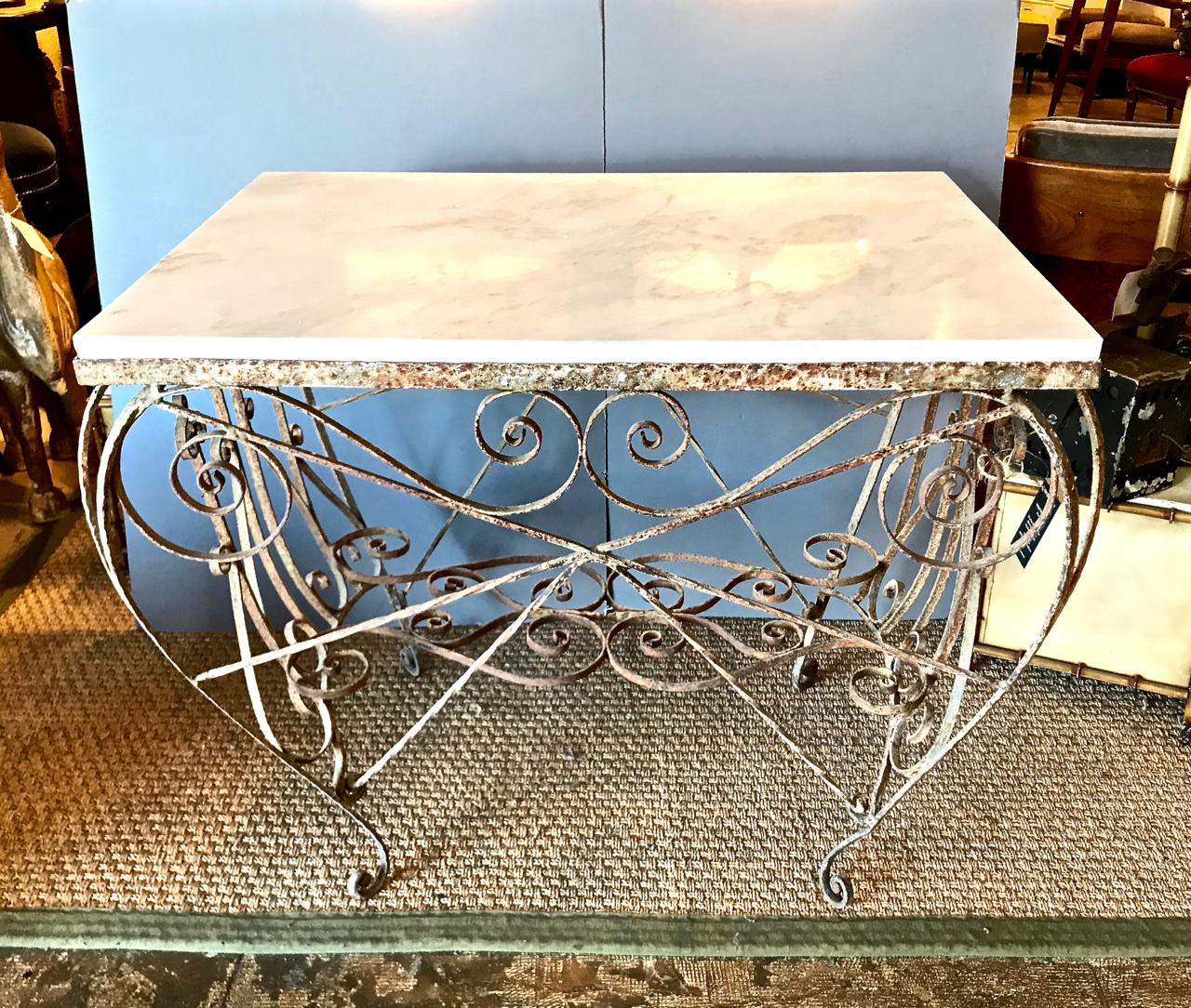 This is an unusual French Pastry or Butcher's table that retains its original surface which has acquired a great natural patina and depth. The marble is 19th century. but not original to the table. The whimsy of the iron work speaks to the