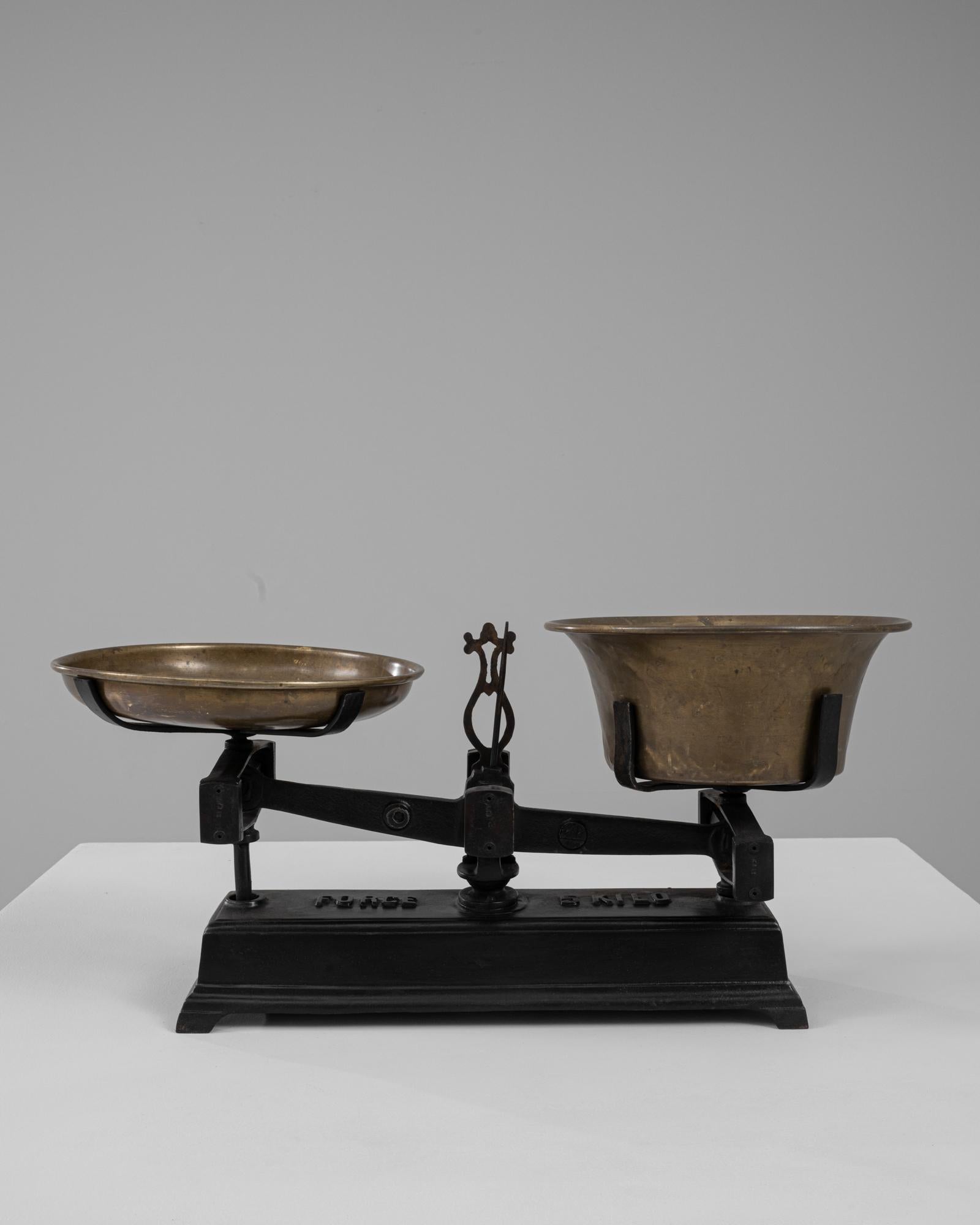 Questa bilancia francese del XIX secolo in ferro e ottone mostra la perfetta unione tra funzione industriale e forma scultorea. La base in ghisa, con la sua scritta in grassetto e l'elegante curvatura, costituisce una solida base per le padelle in
