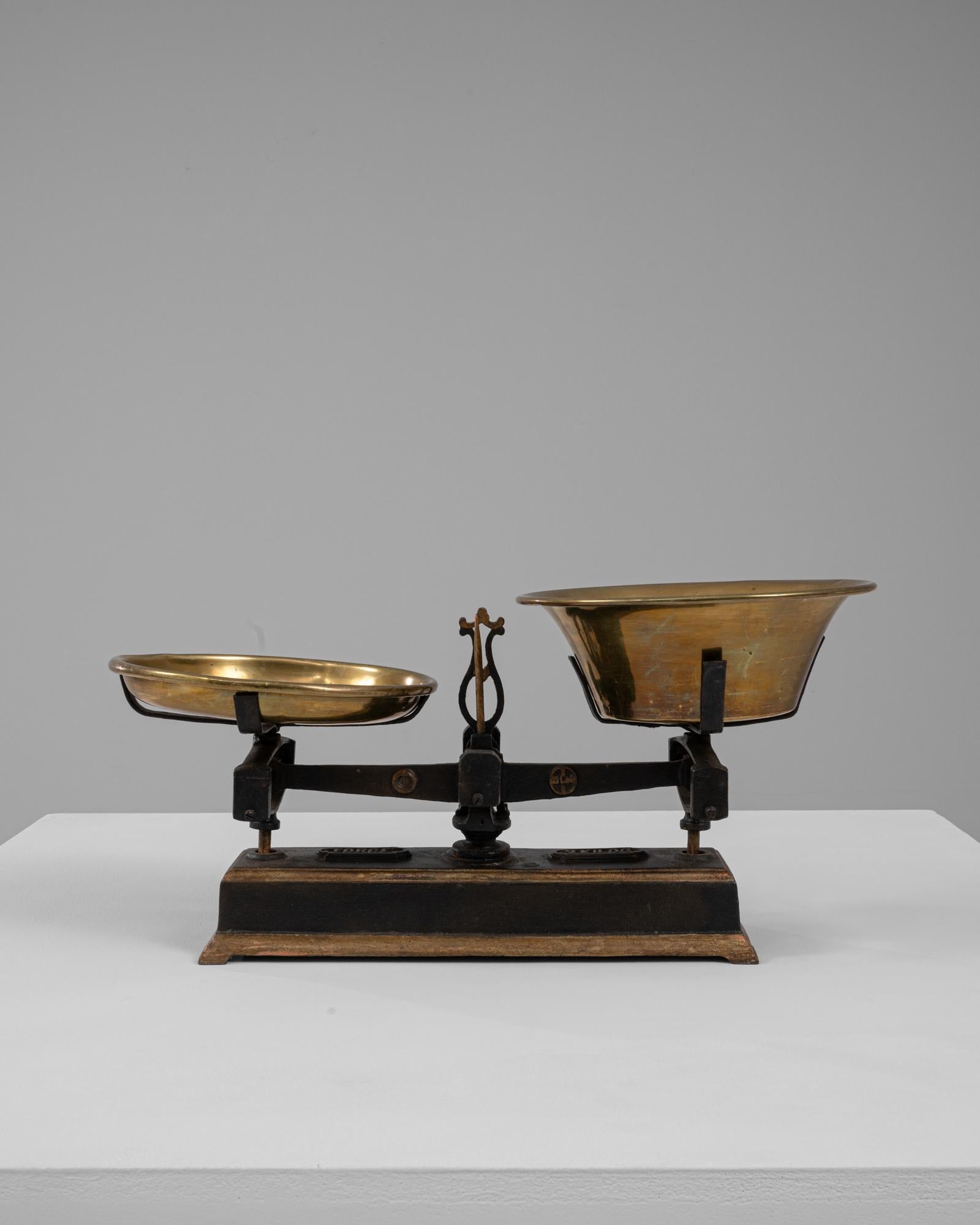 Questa bilancia francese del XIX secolo in ferro e ottone presenta una straordinaria miscela di struttura utilitaria e raffinato contrasto di materiali. La base in ghisa, caratterizzata da linee pulite e da un profilo dolcemente a gradini, conserva