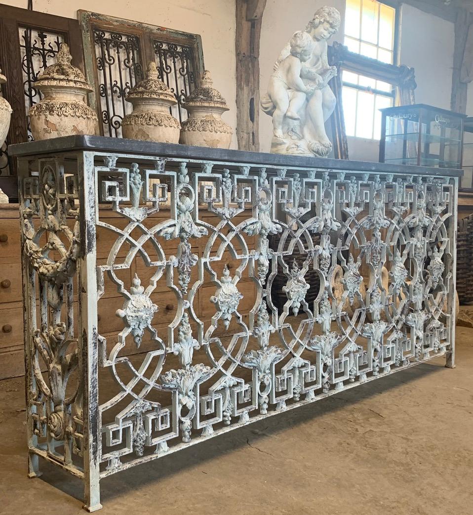 A beautiful French iron balcony console table with a Belgium blue stone top. It has been made from elements of a French balcony and has nice old weathered paint giving it a great look. We have a matching pair of these if you need two.