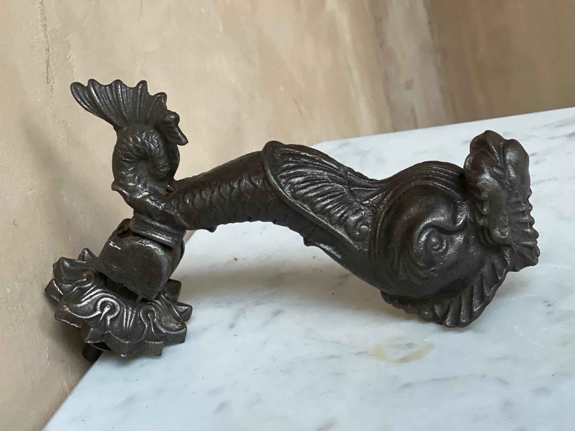 French cast iron door knocker from the late 19th century. The knocker is a figure of a mythological dolphin with a scales and a fan shaped tail.