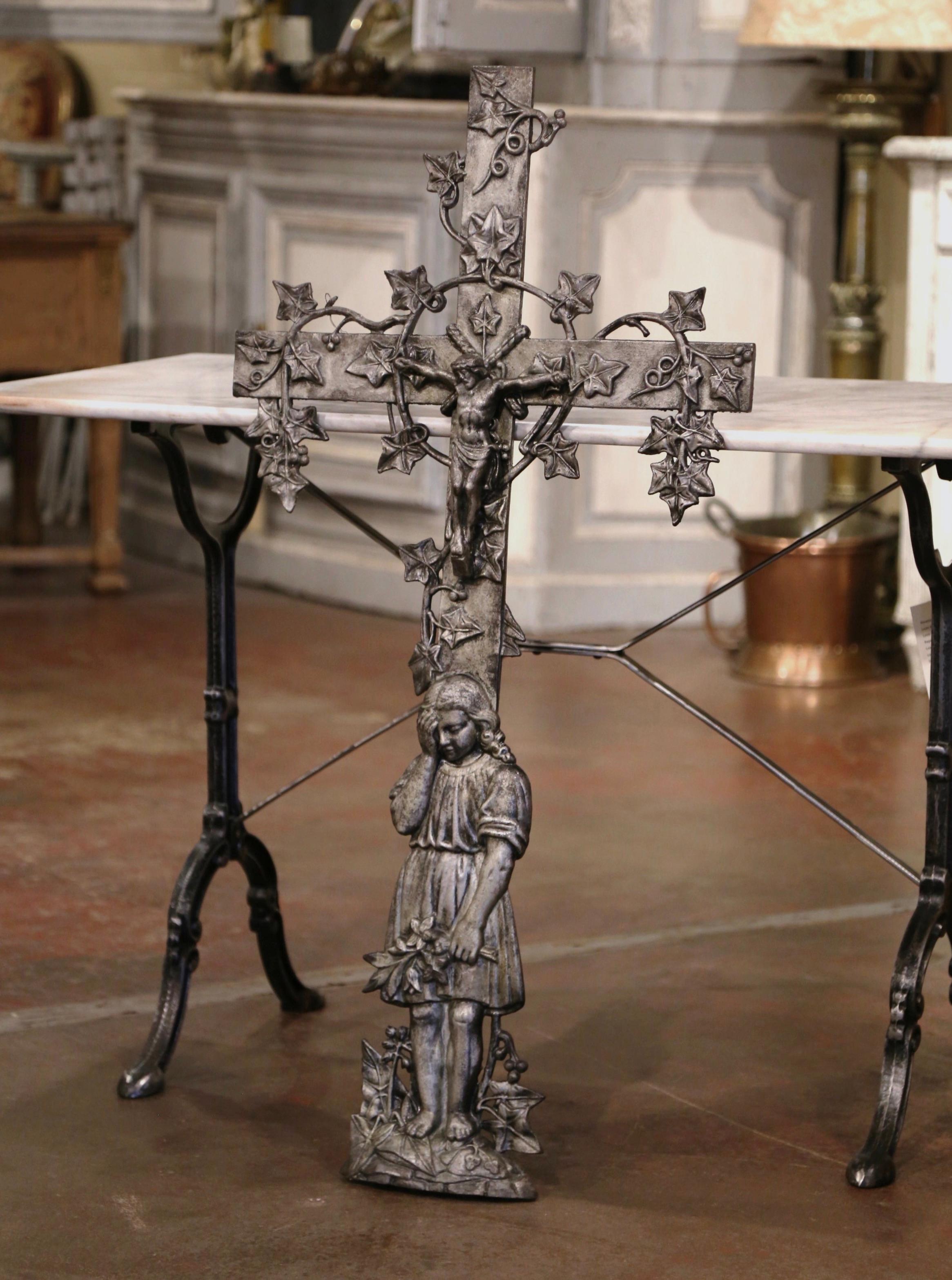 This beautiful, antique cross was crafted in France, circa 1870. The large iron crucifix rests on an oval base, and features our Lord nailed on the cross; the cross is decorated with vine and reed motifs in high relief all throughout, and features a