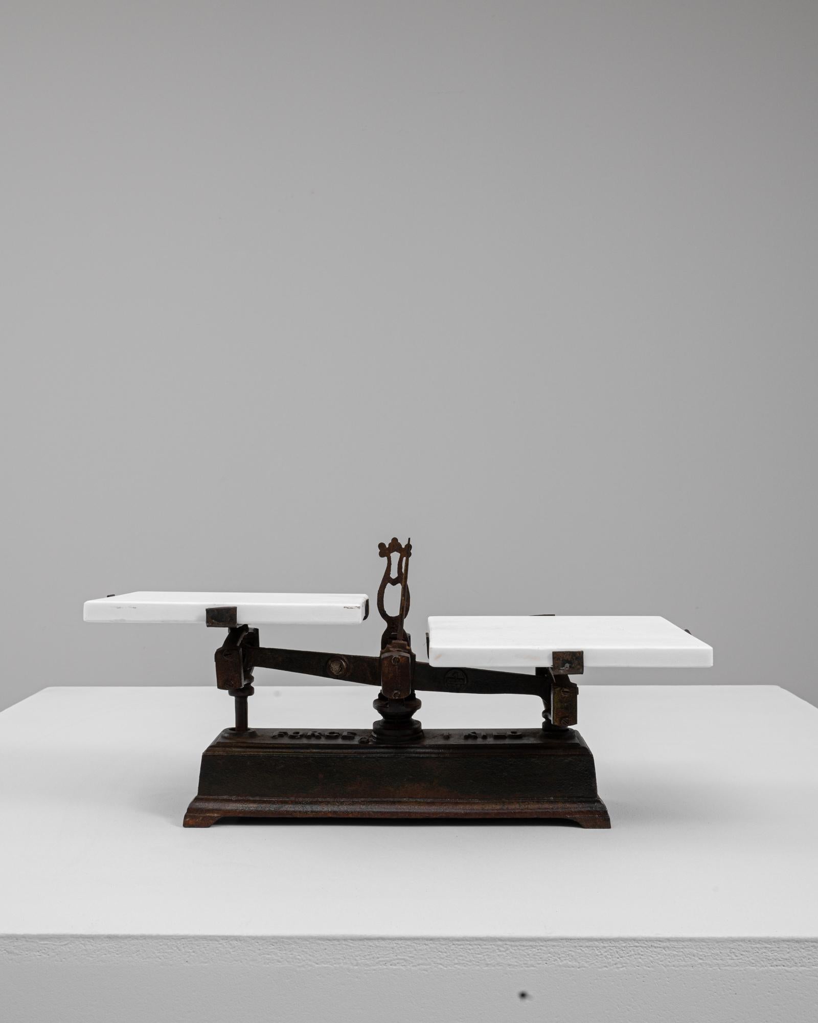 Questa bilancia francese in ferro e marmo del XIX secolo è un esempio lampante di artigianato utilitaristico elevato da materiali eleganti e proporzioni equilibrate. La base in ferro scuro e consumato dal tempo presenta sottili bordi modanati e