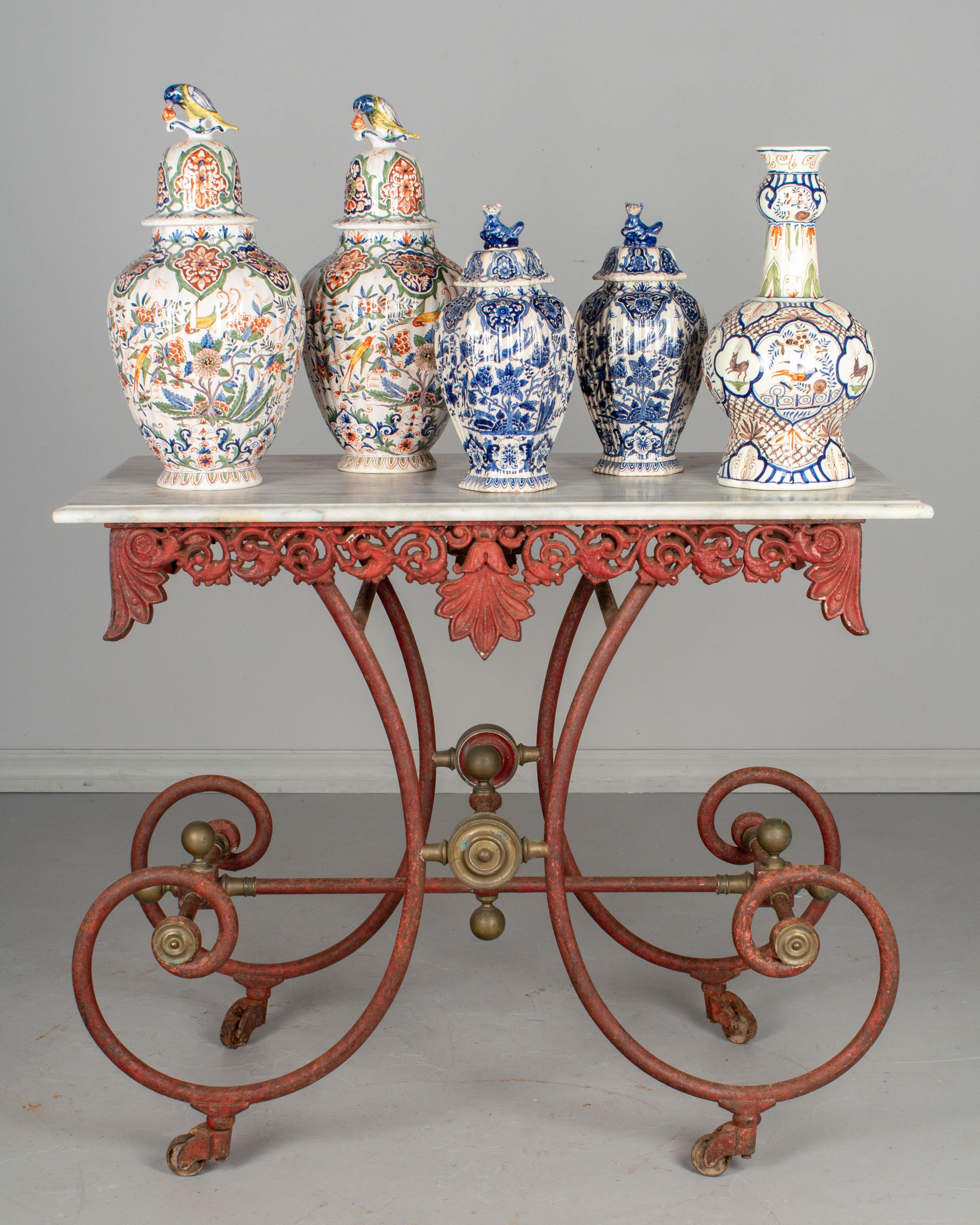 A 19th century French pastry table with original red painted patina. Curved wrought iron base with decorative brass hardware. Ornate cast iron frieze around the perimeter with large acanthus leaves. Original castors. White veined marble top. As