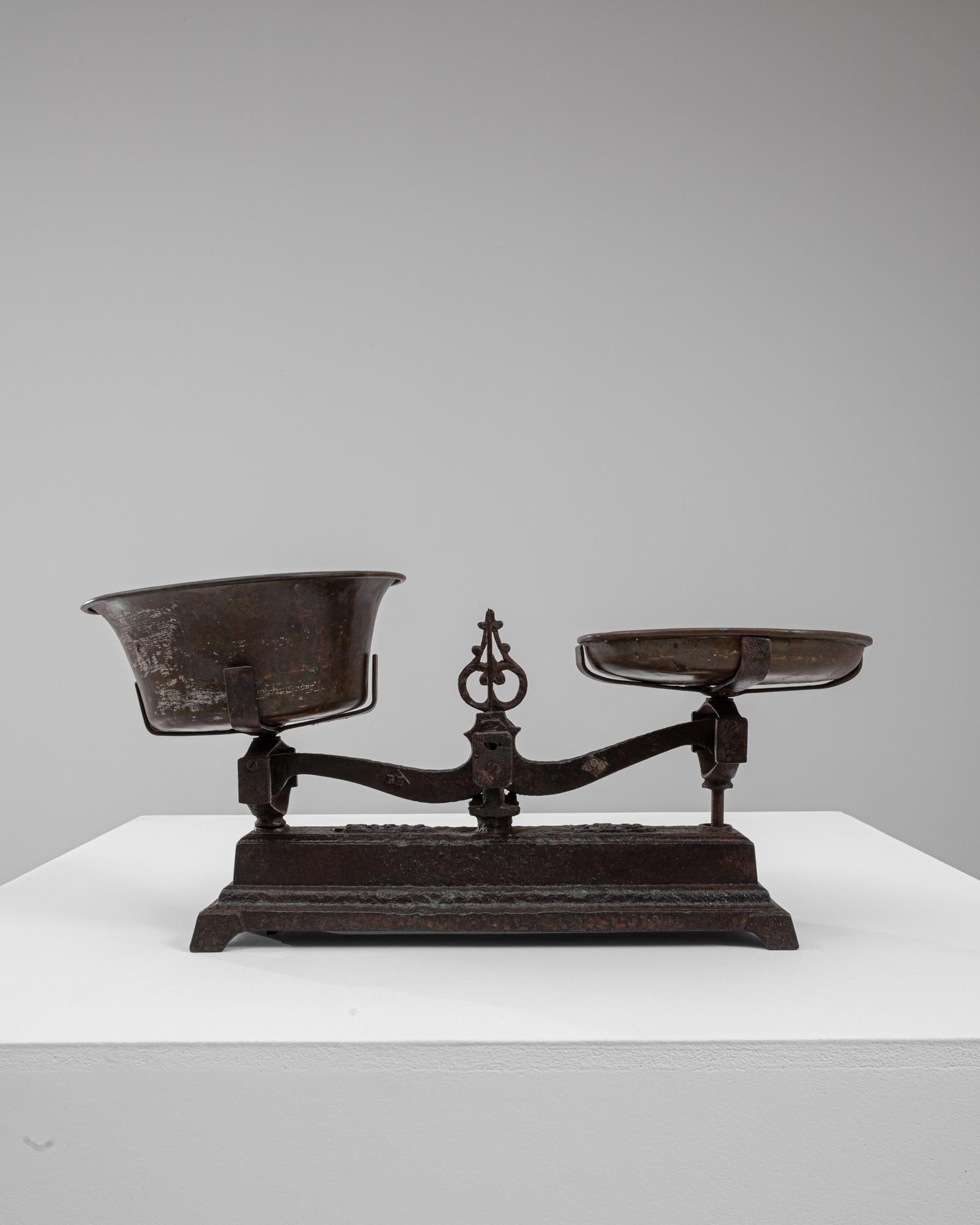 Questa bilancia in ferro francese del XIX secolo mostra un'irresistibile miscela di design utilitario e presenza scultorea, caratterizzata da una forma in ghisa riccamente patinata e da una silhouette graziosamente bilanciata. La base a gradini