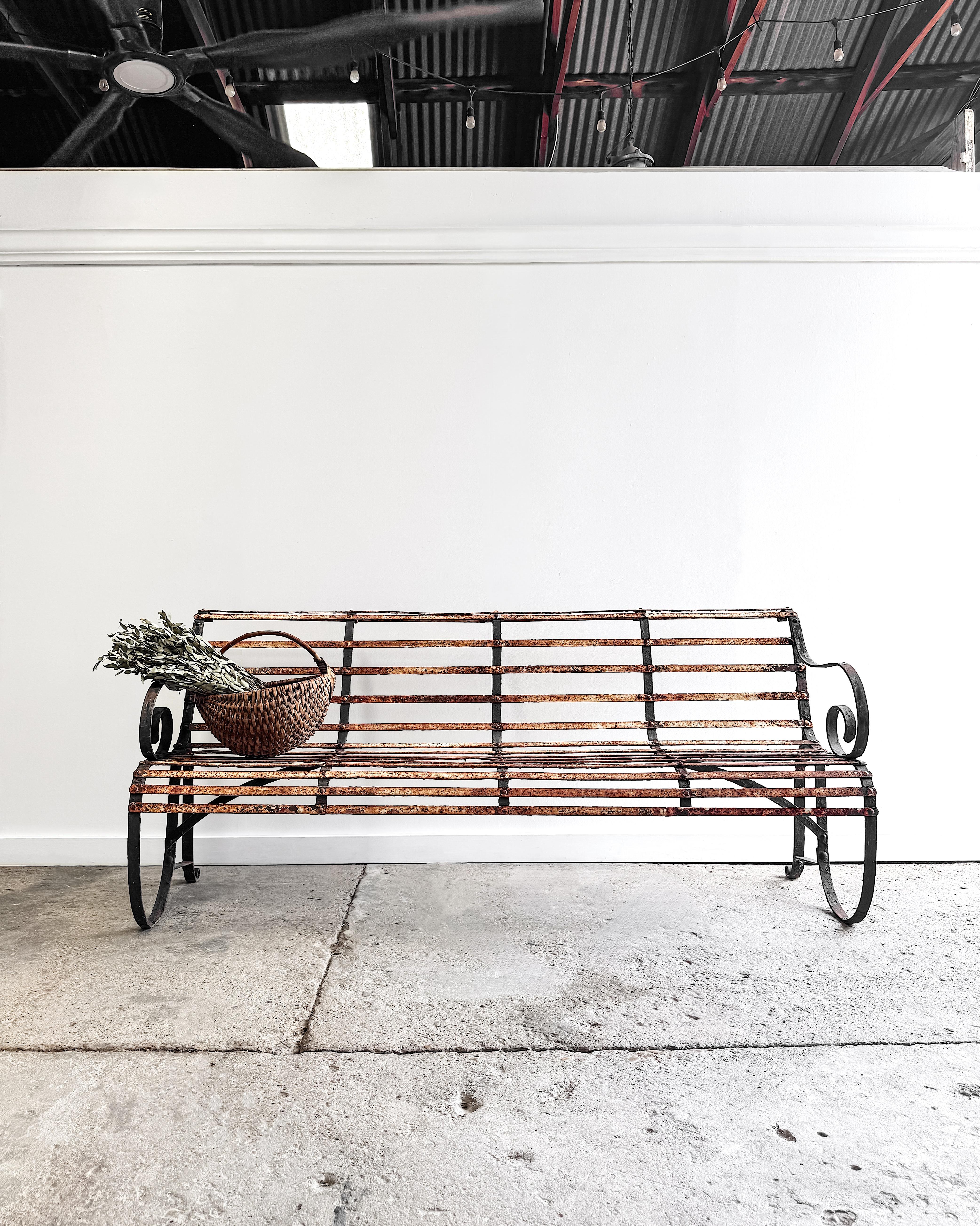 With its graceful lines and weathered patina, this 19th-century iron garden bench brings the poetry of age and craftsmanship to any outdoor setting. 

Hand-forged in France, the bench features a slatted seat and backrest formed from narrow iron