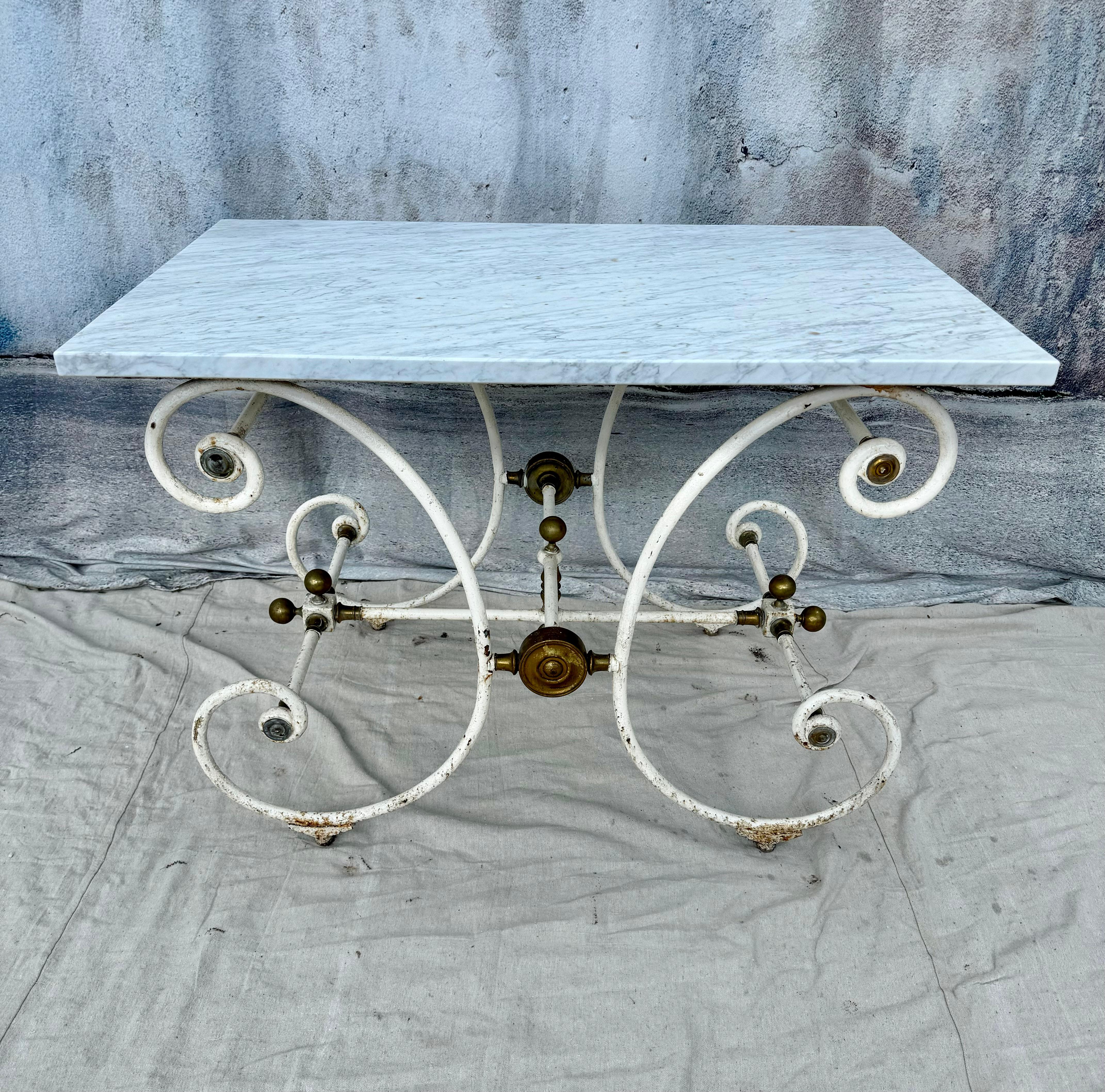 19th Century French baker's table by J. Mareschal, Paris.  Table features classic white marble top and curved wrought iron base. The table has bronze details as a finish. These tables were used for preparing and displaying the finest cuts of meat