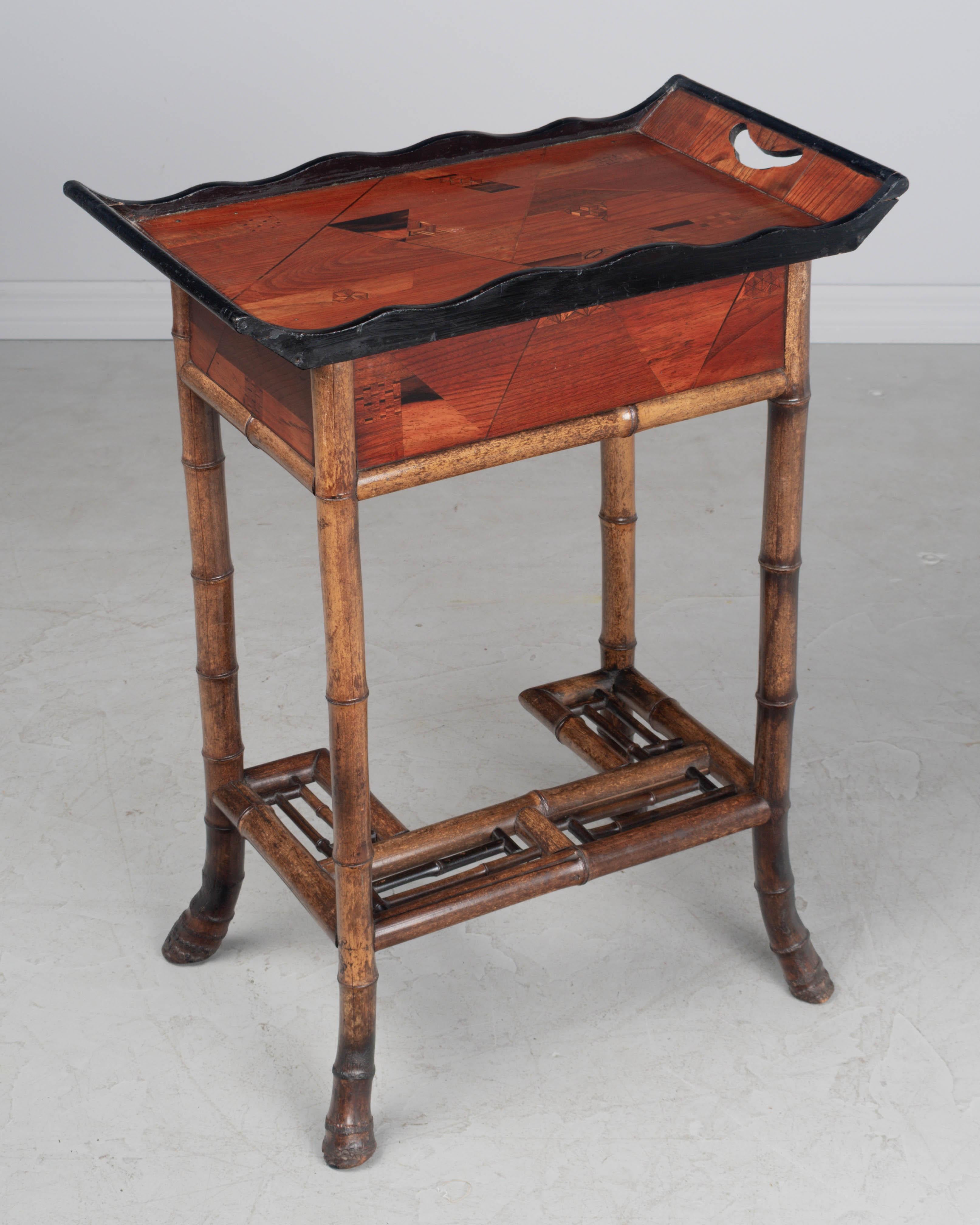 Table d'appoint du mouvement esthétique du japonisme français du XIXe siècle. Cadre robuste en bambou avec un châssis en bambou ajouré et des pieds en racine légèrement incurvés. Le dessus est constitué d'un plateau en bois de rose incrusté de