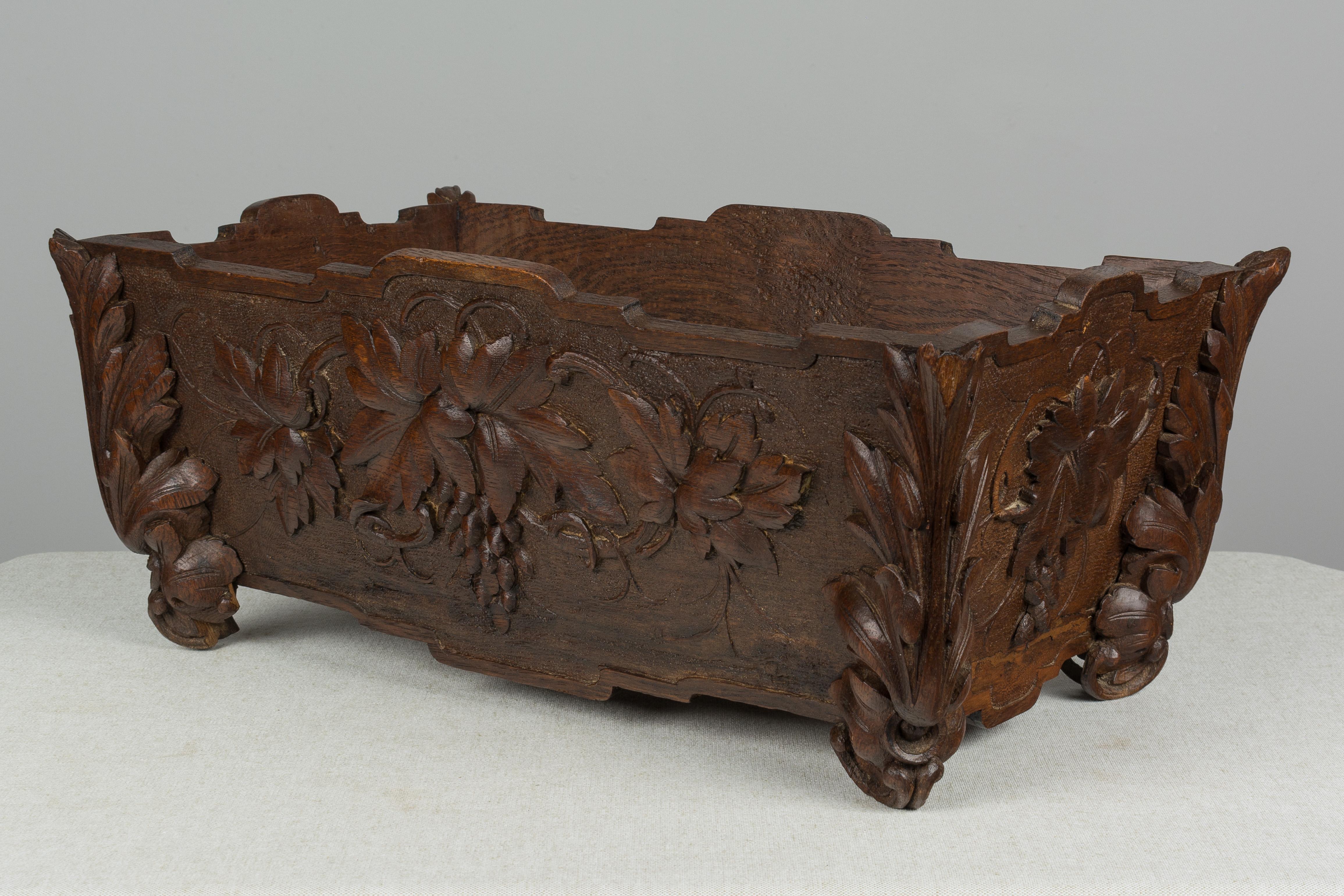 A late 19th century French jardinière or planter made of oak. Beautifully crafted with elaborately carved details including large acanthus leaves on the corners and clusters of grapes on all four sides. Waxed patina. Missing some carvings on the