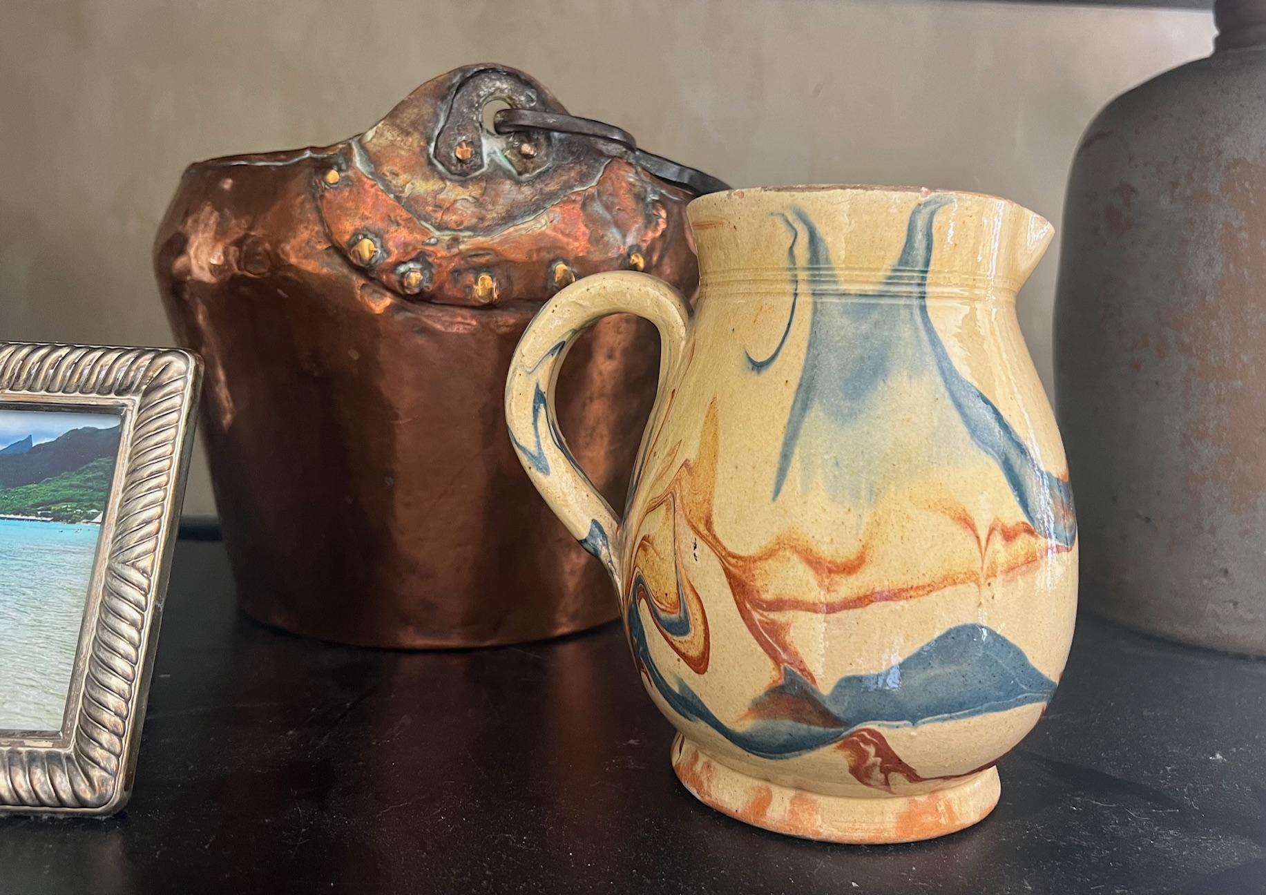 Jaspe terracotta glazed ceramic country pitcher with a background of butter yellow with a swirl pattern of blue and burnt umber. Made in the Savoie region of France toward the end of the 19th Century.

Jaspe pottery is typically marble-like swirls