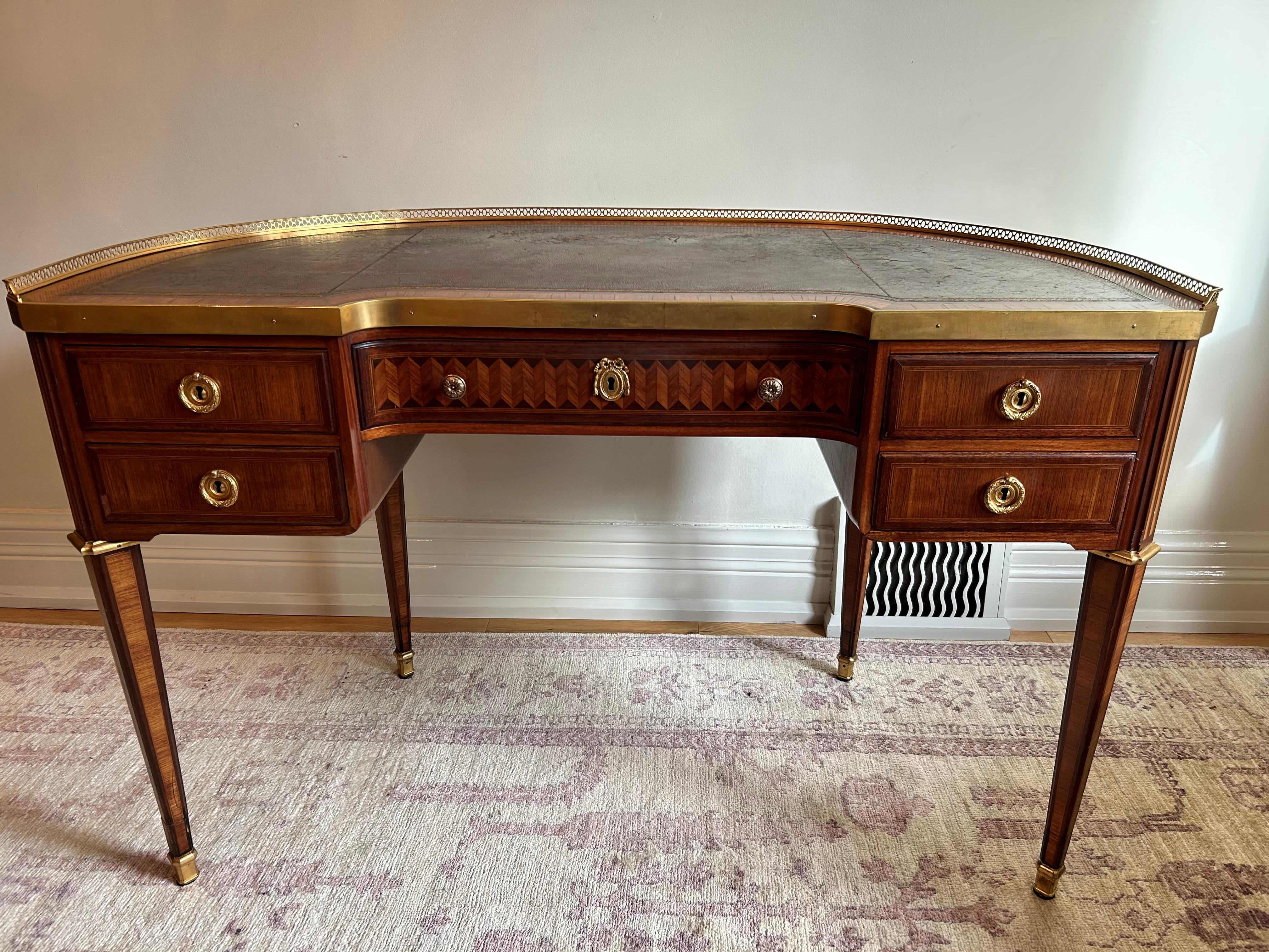 Late Nineteenth century kidney shaped desk in the stule of Louis XVI. Exquisite marquetry  on the front drawers and throughout, with book matched satinwood veneers on the back. Gilt bronze galleried top and banding. Tapered legs ending in bronze