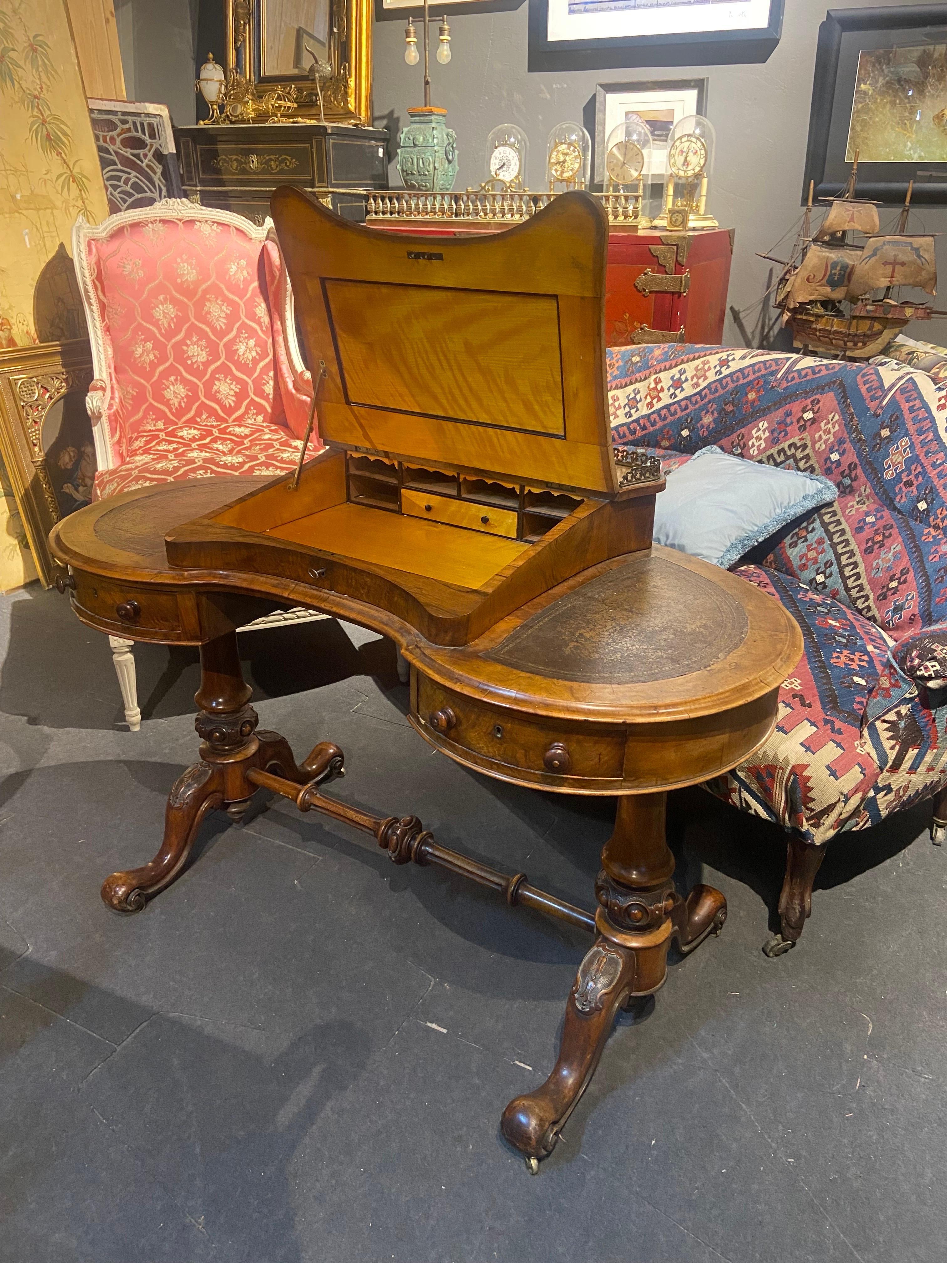 French kidney-shaped veneer writing table, topped with a leather-covered desk and opening with two belt drawers.
Molded base joined by spacer and finished with casters. Decorated with foliage, openwork brass gallery. The piece is in good overall