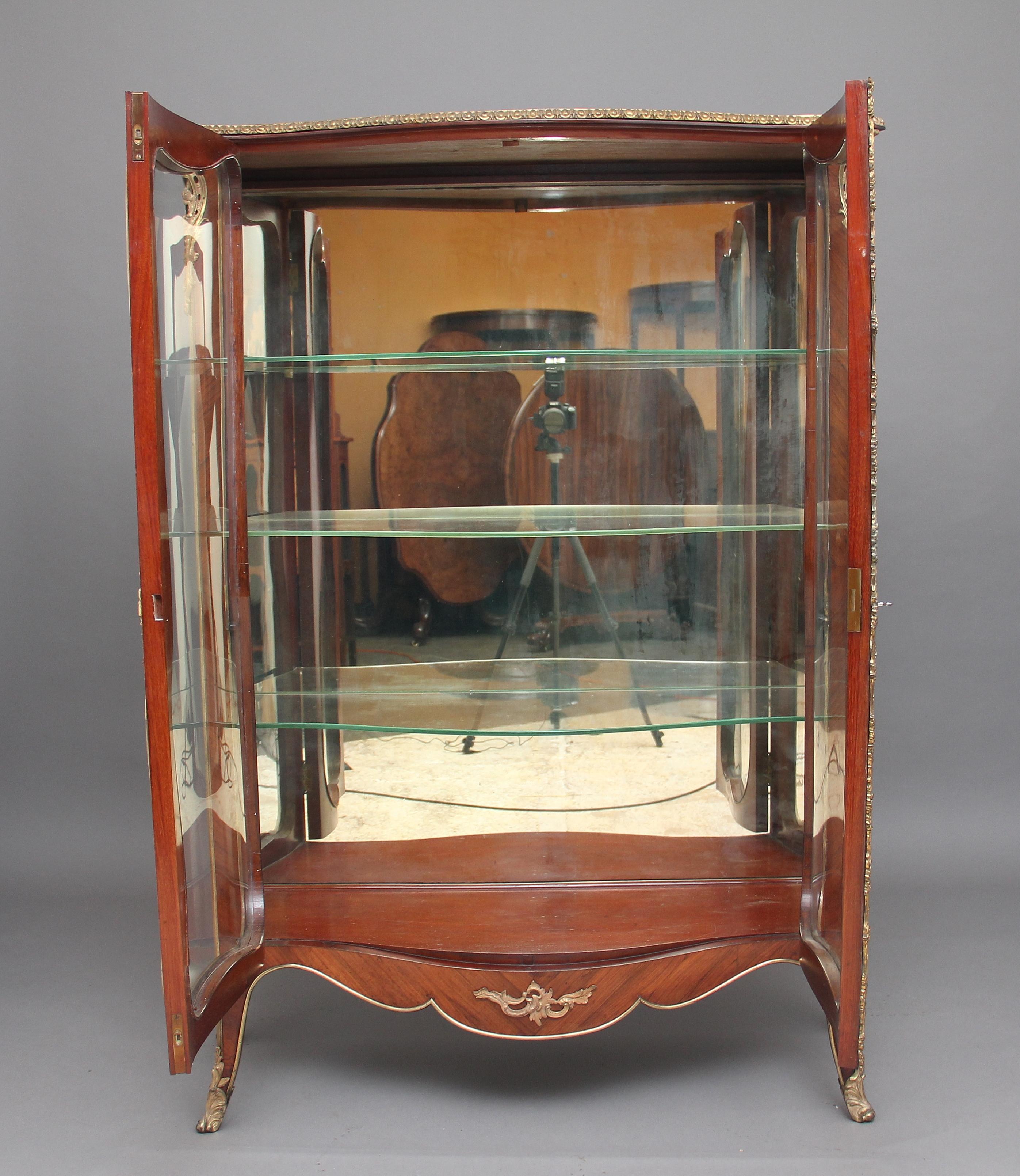 A fabulous quality 19th century French Kingwood and ormolu display cabinet, having a lovely figured shaped top with ormolu moulding at the front and sides, the two doors at the front having lovely shaped glass and this is the same at the sides of