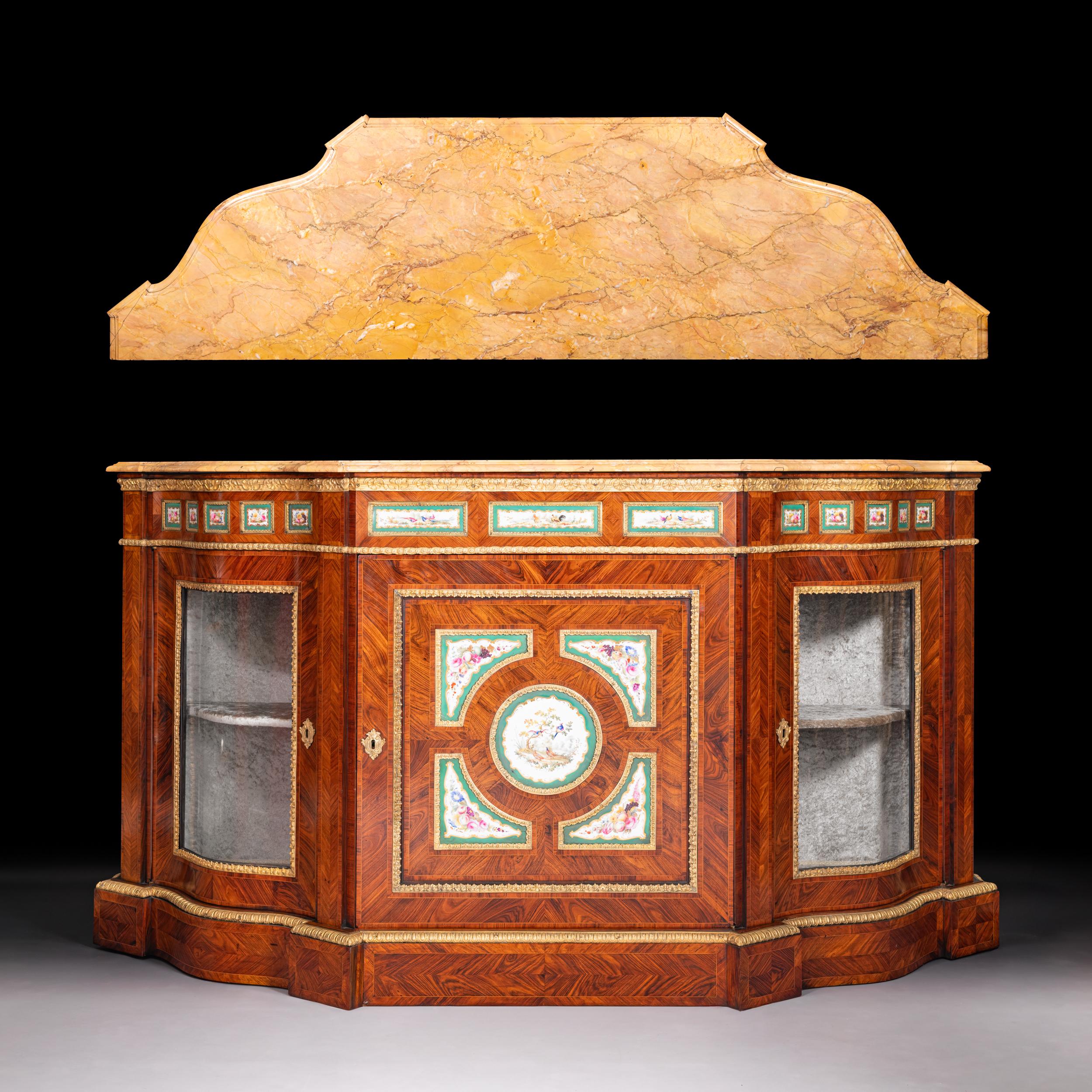 An imposing 19th century Kingwood, Sevres plaques and ormolu mounted credenza of serpentine form, the wonderful Sienna serpentine shaped moulded top above the shaped frieze below decorated with three rectangular hand painted Sèvres plaques flanked