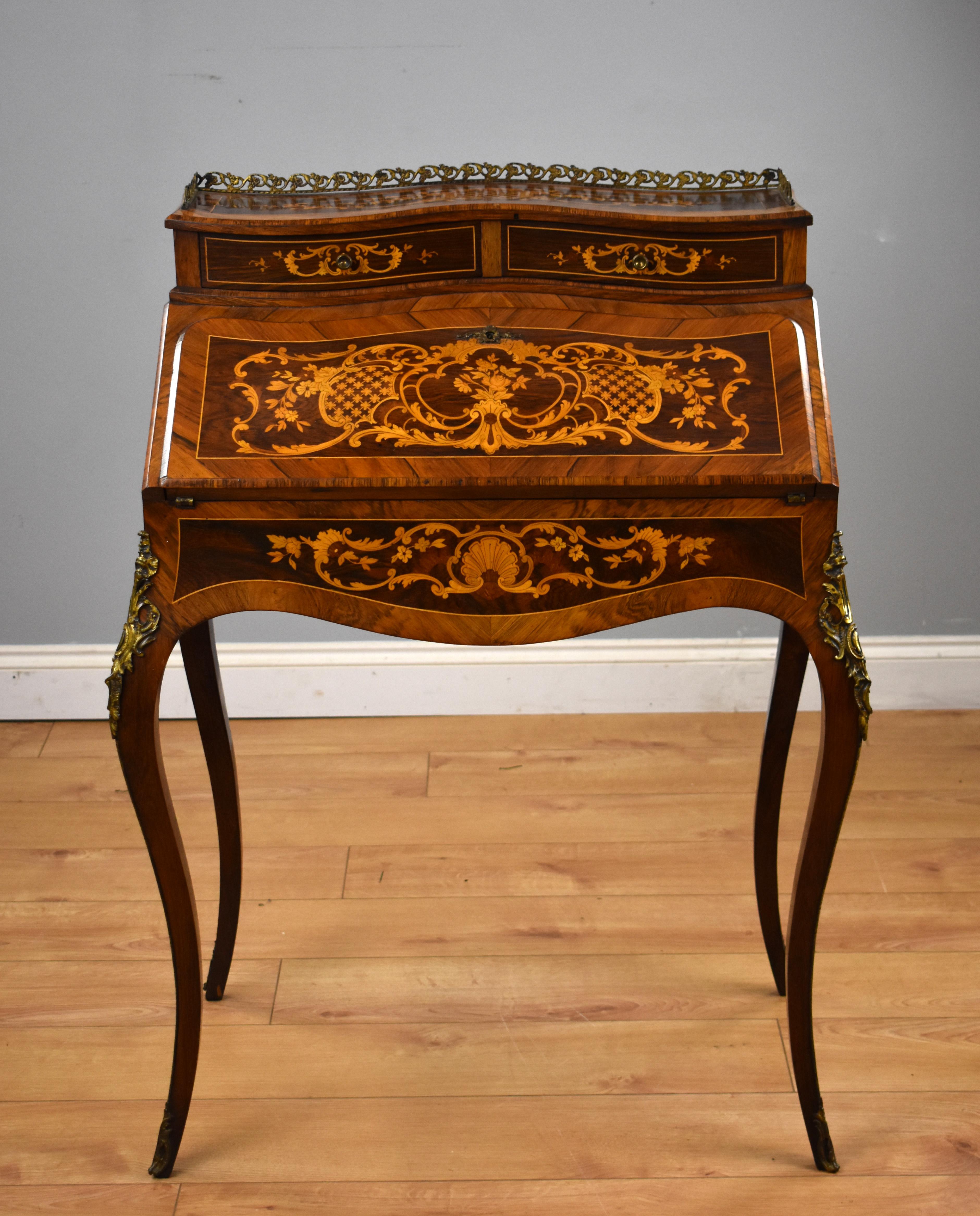 For sale is a good quality 19th century French bureau de dame, having an inlaid shaped top surrounded by an ornate brass gallery, with a fall front below opening to a fitted interior comprising of several drawers and sliding writing surface. The