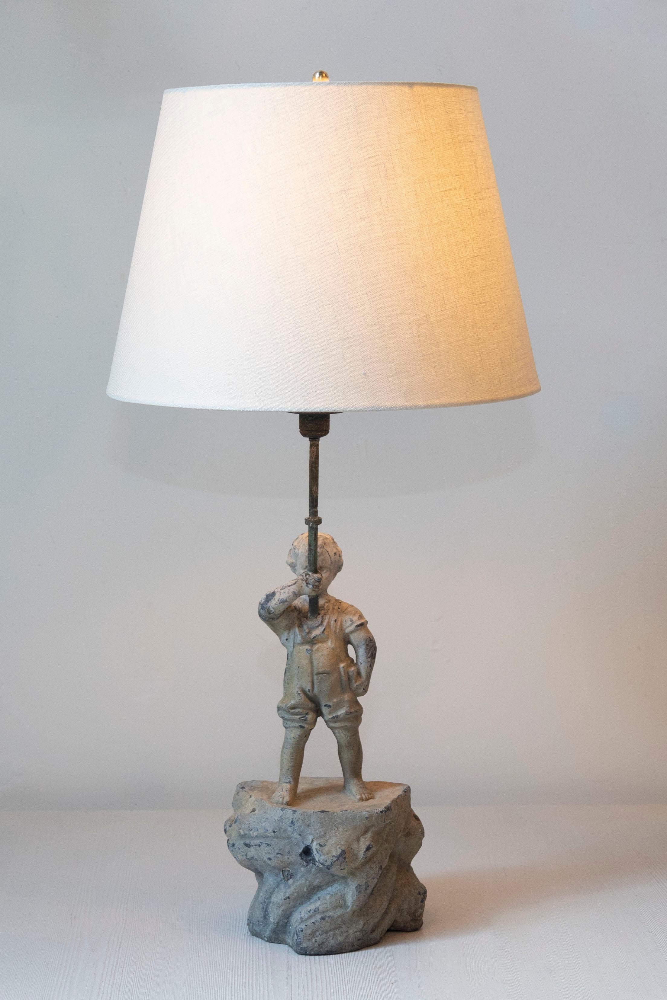Esta lámpara francesa del siglo XIX es una encantadora mezcla de encanto rústico y arte escultórico, lo que la convierte en una pieza decorativa destacada. La base presenta una detallada escultura de un niño de pie, seguro de sí mismo, sobre una