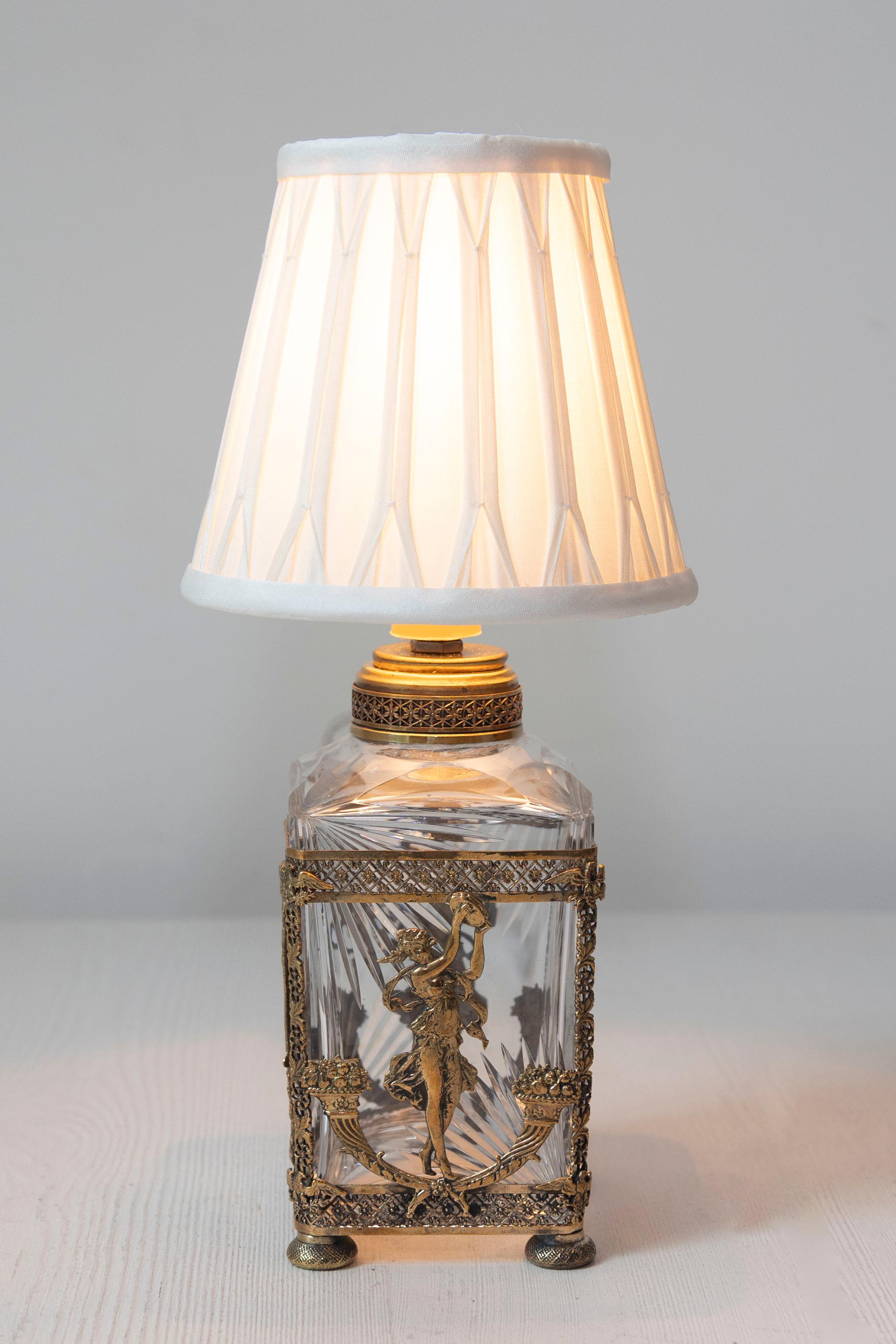Questa squisita lampada francese del XIX secolo è un capolavoro del design neoclassico, che combina materiali lussuosi con un'intricata lavorazione artigianale. La base è realizzata in cristallo finemente tagliato, con eleganti motivi sfaccettati