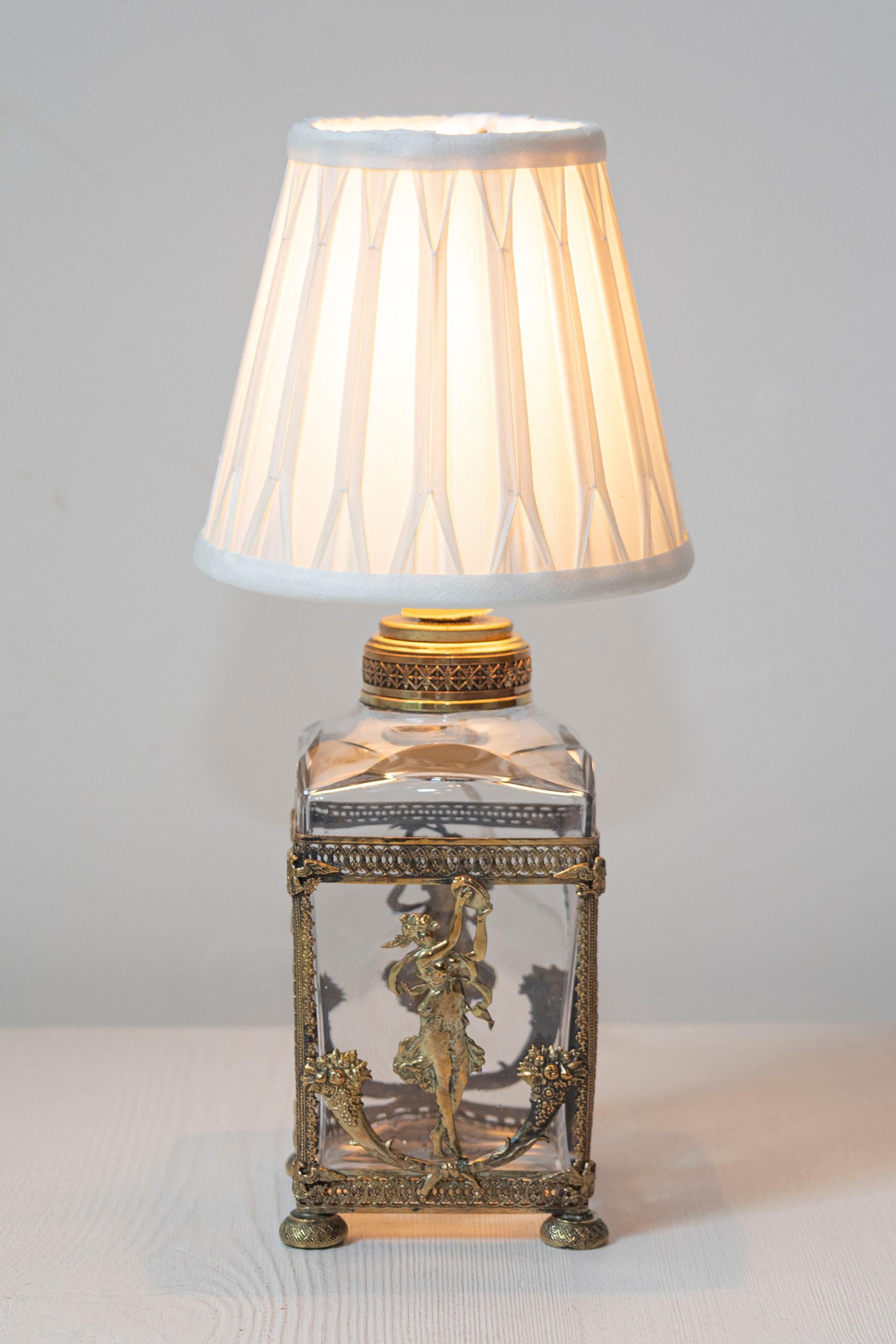 Esta exquisita lámpara francesa del siglo XIX muestra una artesanía y una elegancia artística excepcionales. La lámpara presenta una base de cristal encerrada en un ornamentado marco de bronce dorado, adornado con intrincados motivos florales,