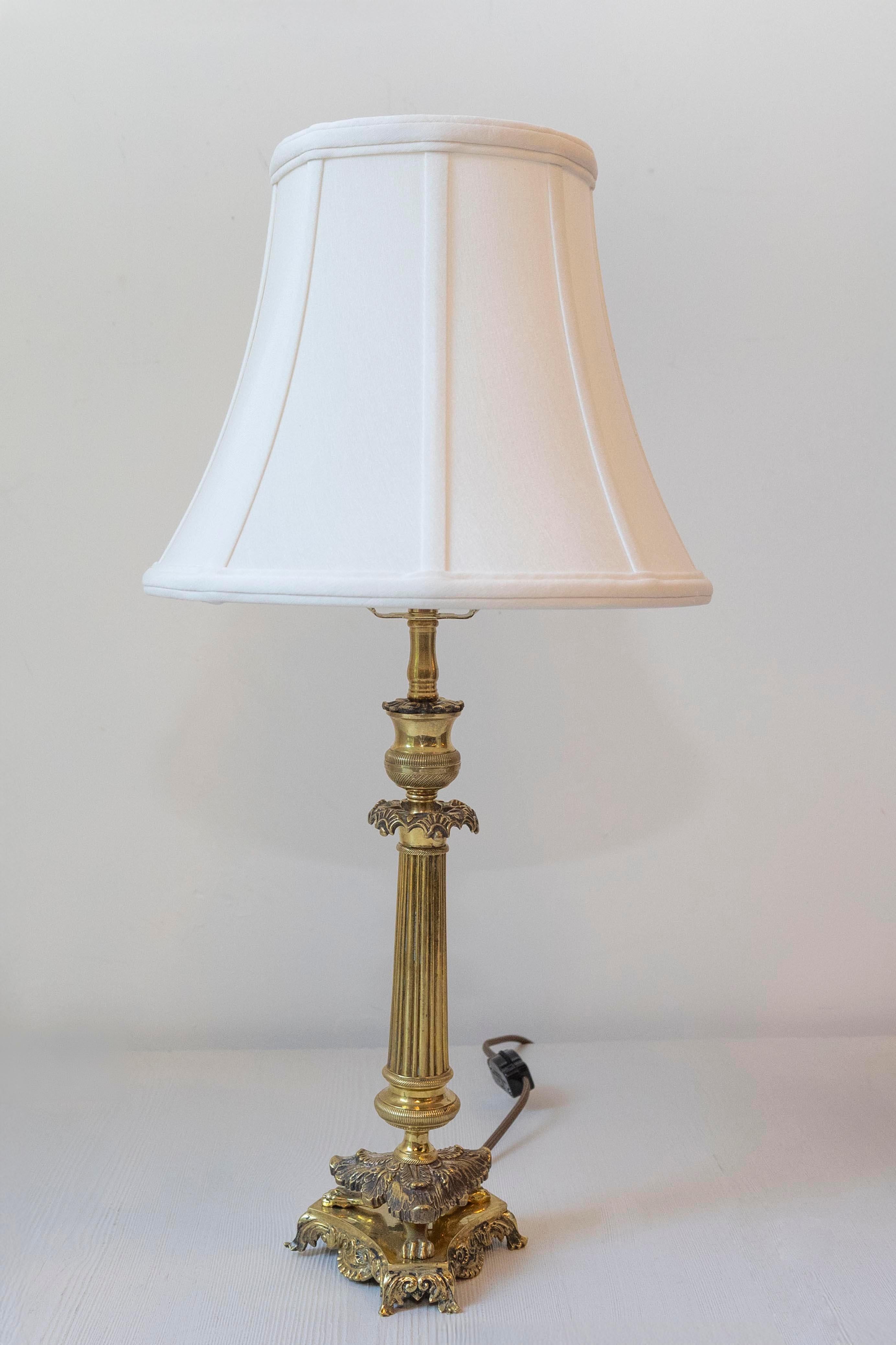 Questo candeliere in stile Eleg del XIX secolo, realizzato in bronzo lucido in una tonalità dorata, è stato sapientemente riadattato come elegante lampada. Con motivi classici dell'Impero, presenta una base a treppiede a zampa di leone che emana