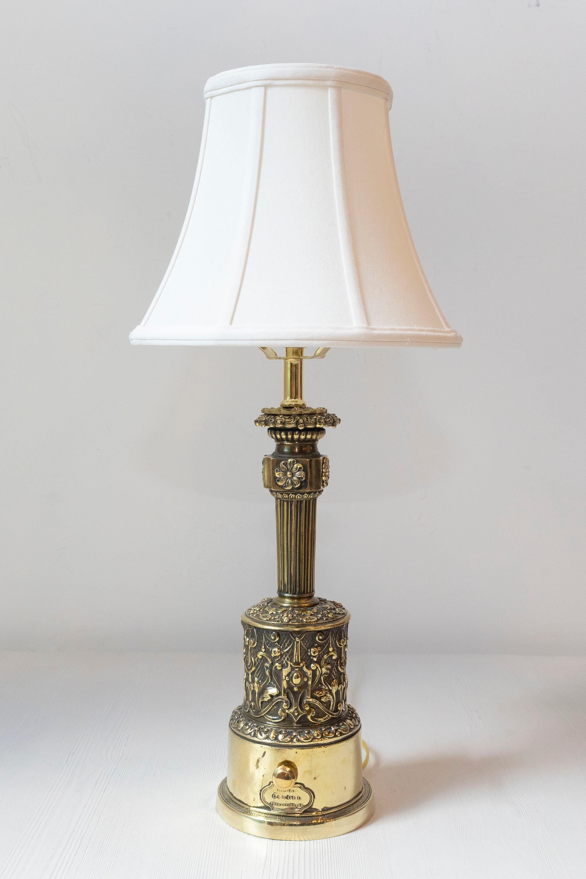Esta elegante lámpara Carcel del siglo XIX, diseñada originalmente para queroseno, ha sido expertamente reconvertida para la electrificación moderna conservando su encanto antiguo. Fabricada en latón pulido y repujado, la lámpara presenta