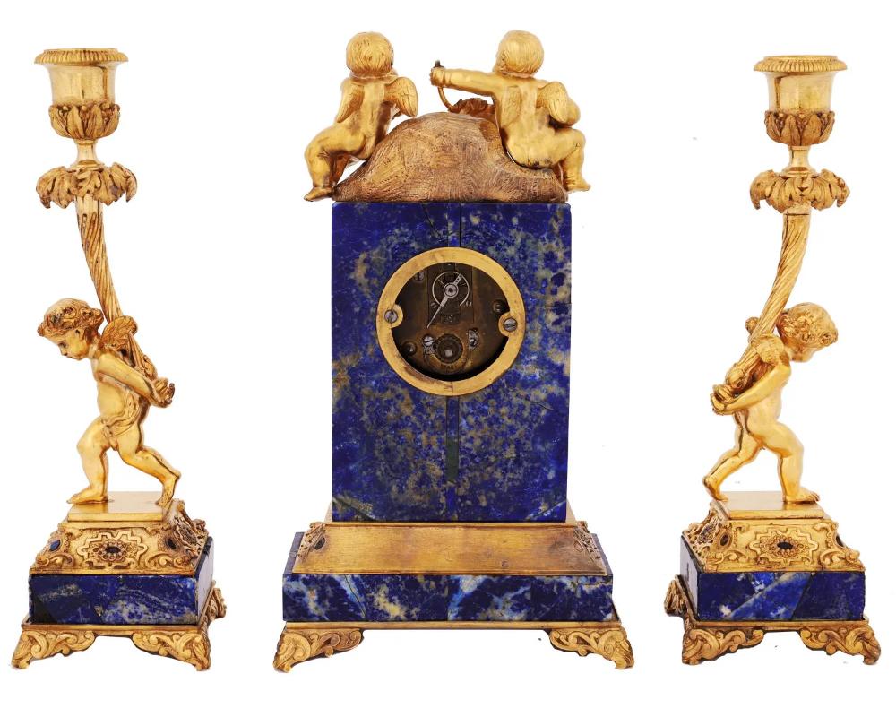 Pendule et chandeliers en Lapis et Ormolu du 19ème siècle avec des chérubins.

En très bon état prêt à plaire quelques petits lapis manquants vous pouvez voir dans les photos.

L'horloge mesure approximativement :9 ½ pouces de haut par 5 ½