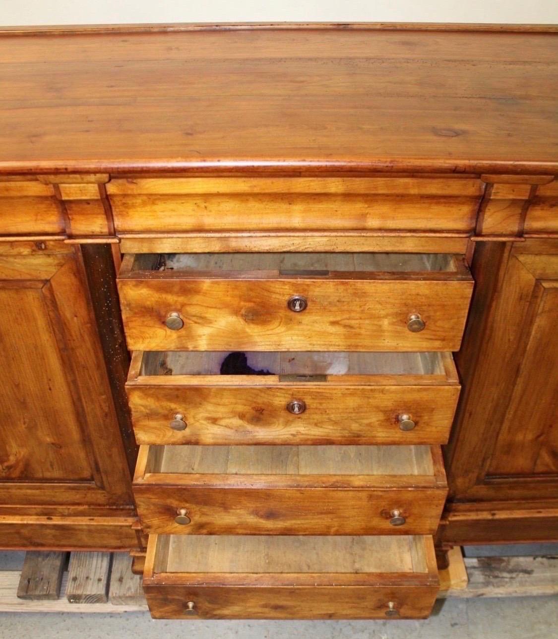 This stunning Early 19th Century French Directoire Fruitwood Enfilade offers both elegance and practicality, making it a perfect addition to any space in need of stylish storage. Featuring four spacious center drawers and cabinet doors on each side,