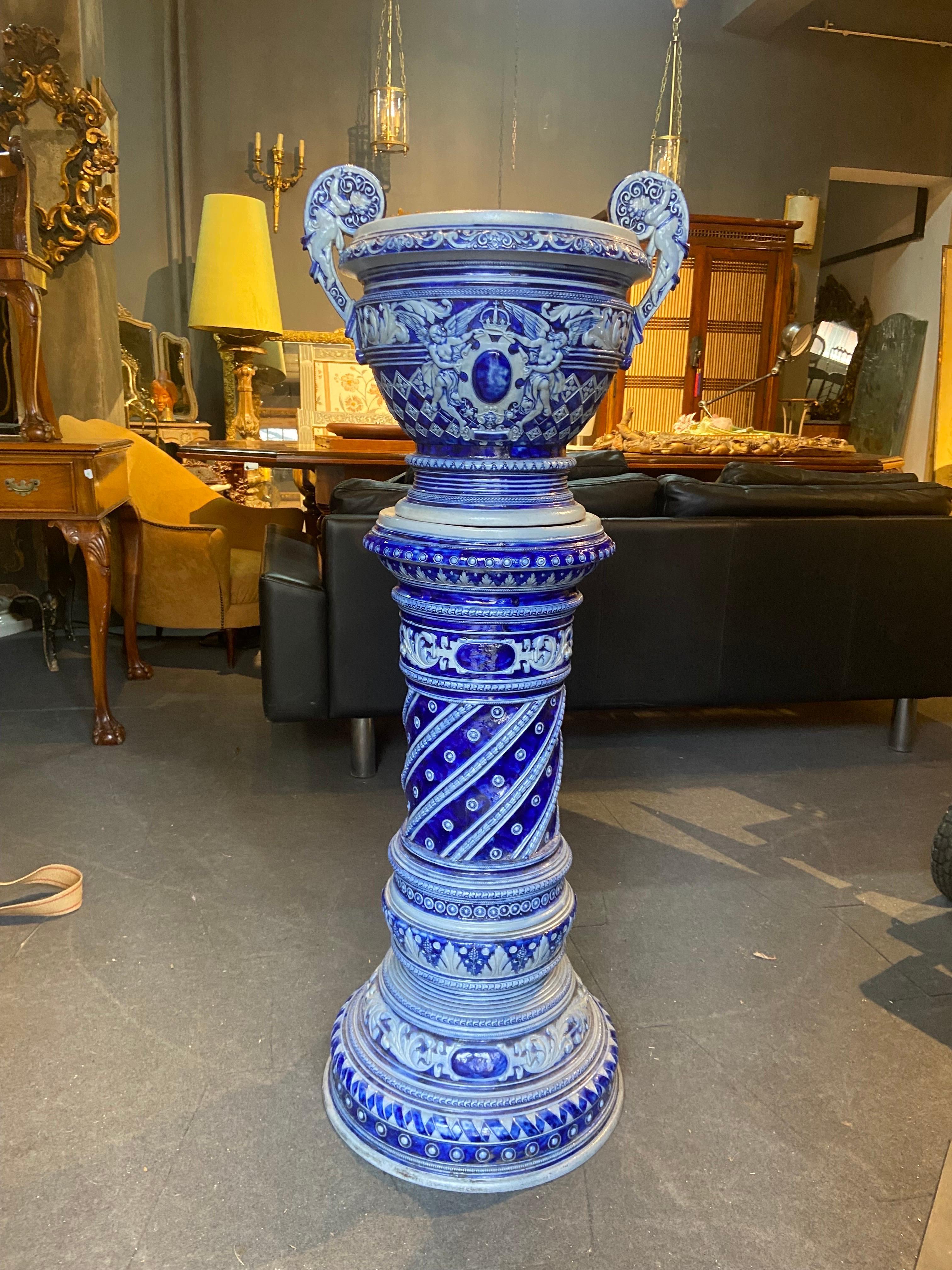 Here we present a real piece of art! Unique hand made ceramic jardiniere in two pieces. There is a large stable base decorated with floral and geometrical elements in blue and white. Over the base there is the oval part with two handles with cupids