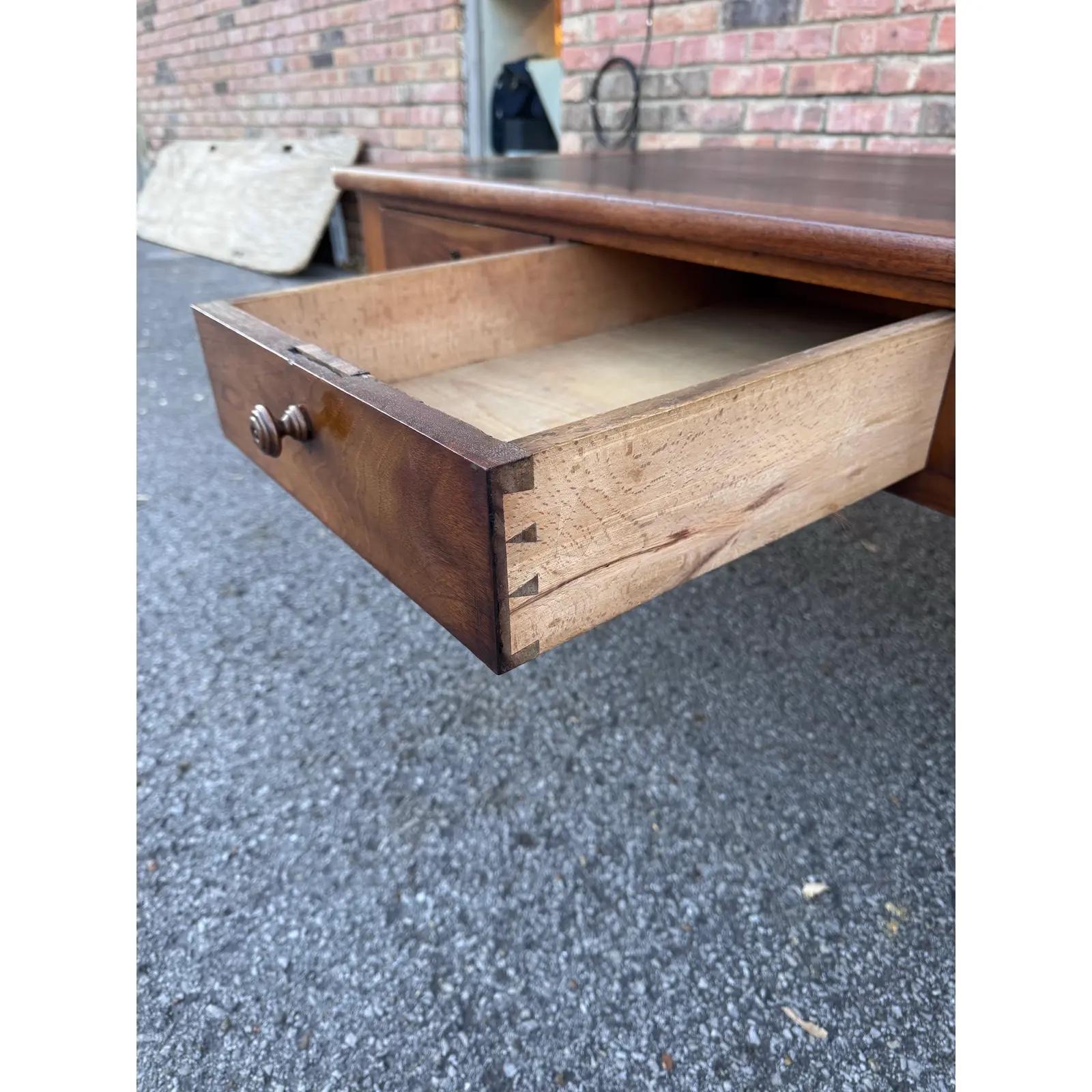 Mesa de centro de madera antigua recuperada con tapa de cuero. La mesa de centro tiene un diseño tradicional de época con. Tres cajones pequeños, dos de ellos con cerradura . Los pies se han vuelto detallistas. La parte superior lleva cuero oscuro