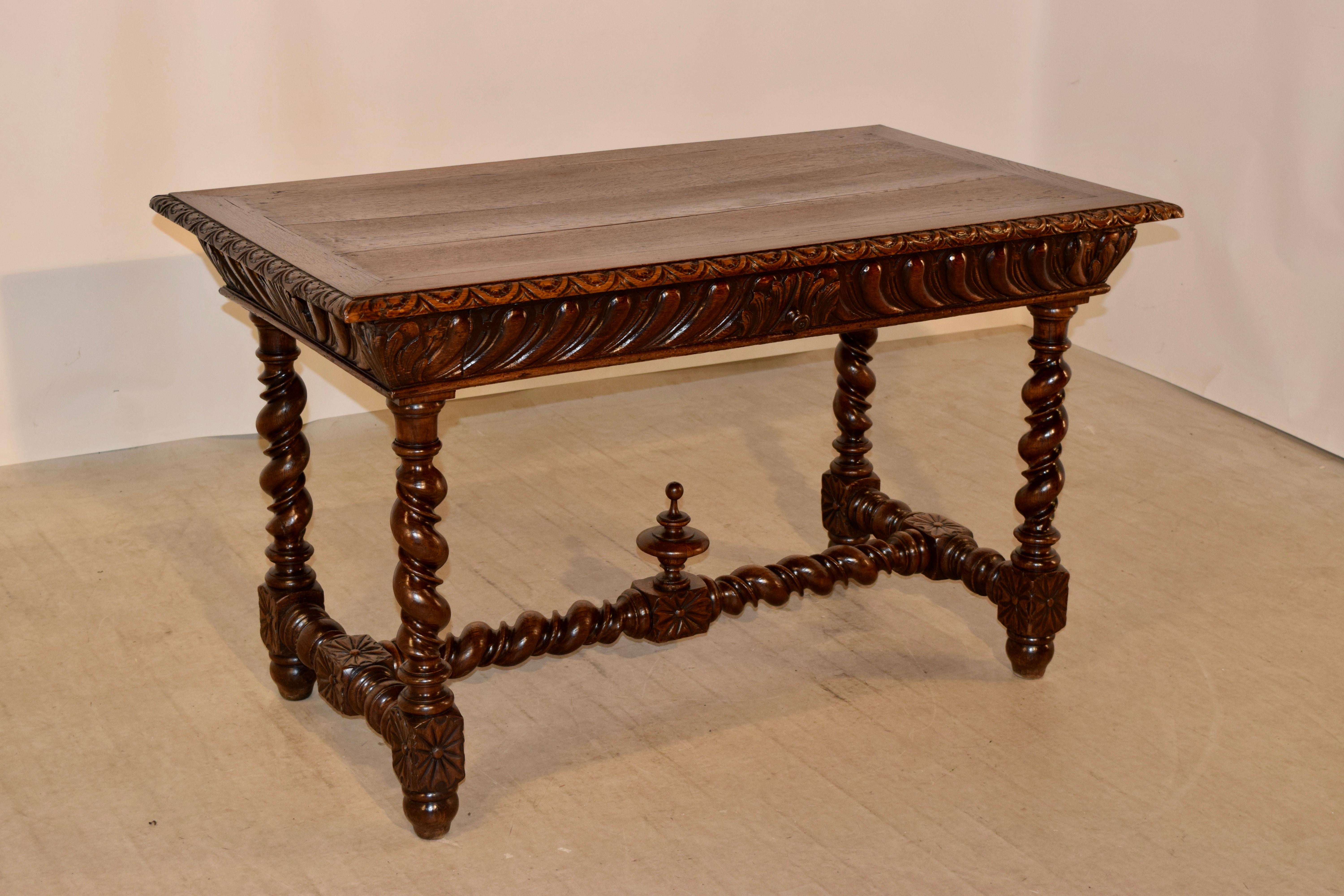 19th century oak library table from France with banded edges around the top which also has a beveled and carved decorated edge. The apron is hand carved and contains a single drawer in the front and is carved on all four sides for easy placement in