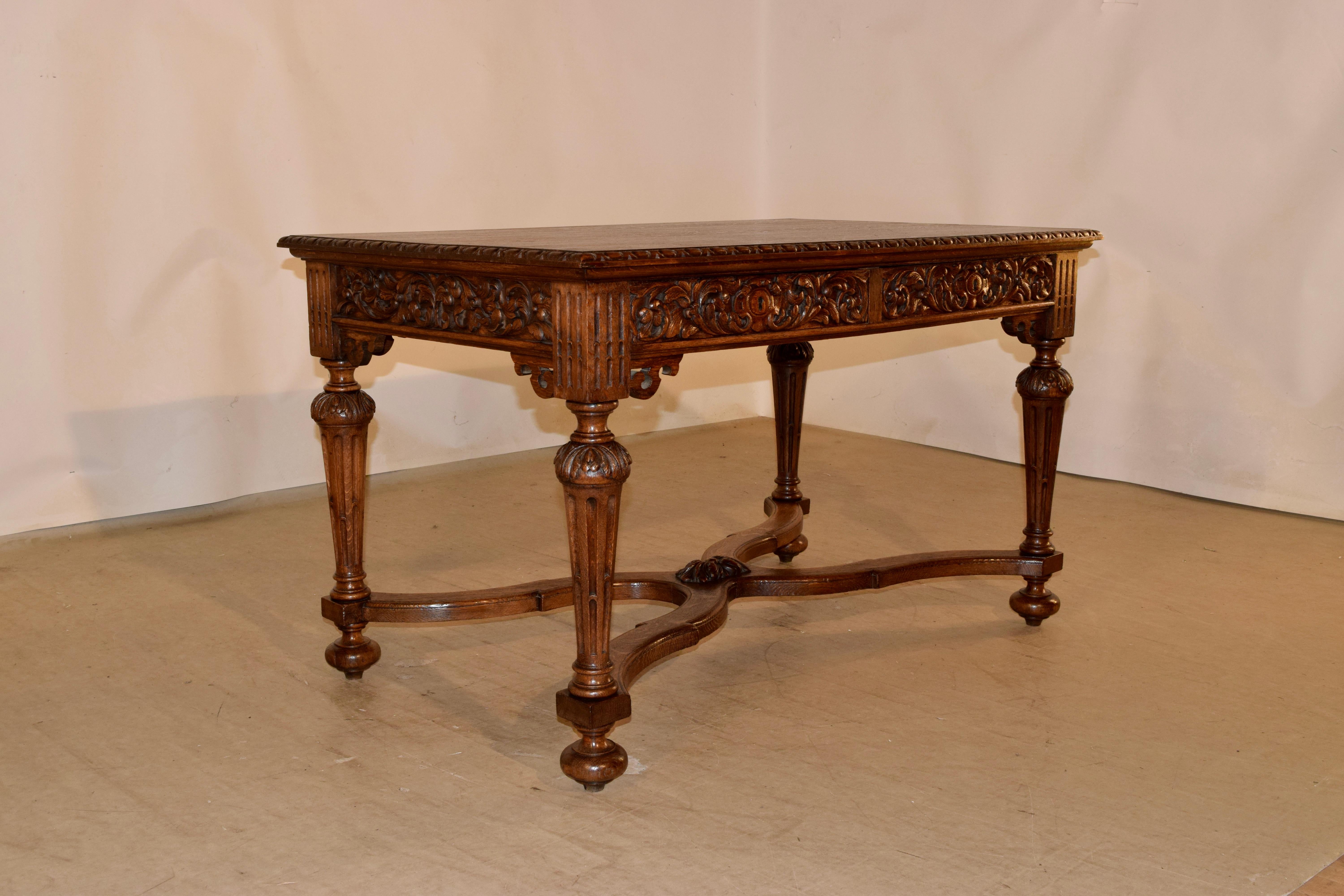 19th century library table from France with a hand carved decorated and beveled edge around the top, following down to a heavily carved apron on all four sides for easy placement in any room. The carving is of acanthus leaves and florals. There are