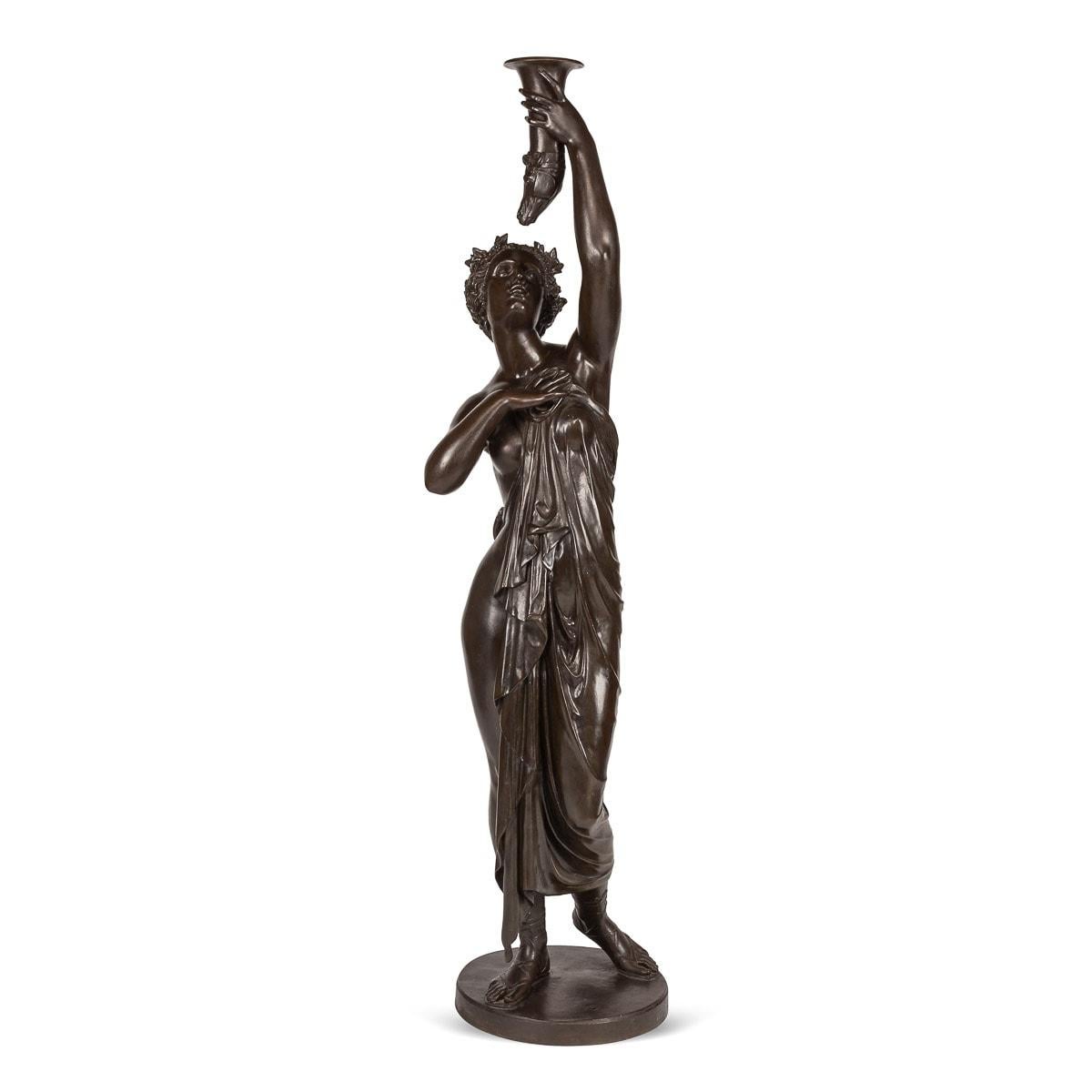 Antique 19th Century French pair of life-sized bronze, depicting partially nude maidens elevating a torch. These statues, boasting a commanding stature and large presence, are elegantly draped in robes. Atop each figure rests a crown of verdant