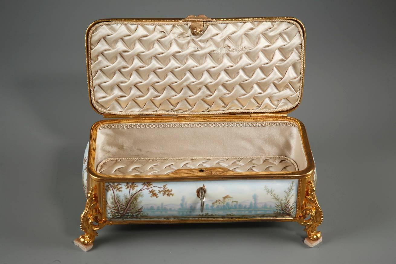 Rectangular Limoges enamel box with its key and gilt bronze mounts. The box rests on four curved, sweeping feet that are richly decorated with volutes and foliage. The entire surface of the lid is decorated with a scene depicting two characters on a