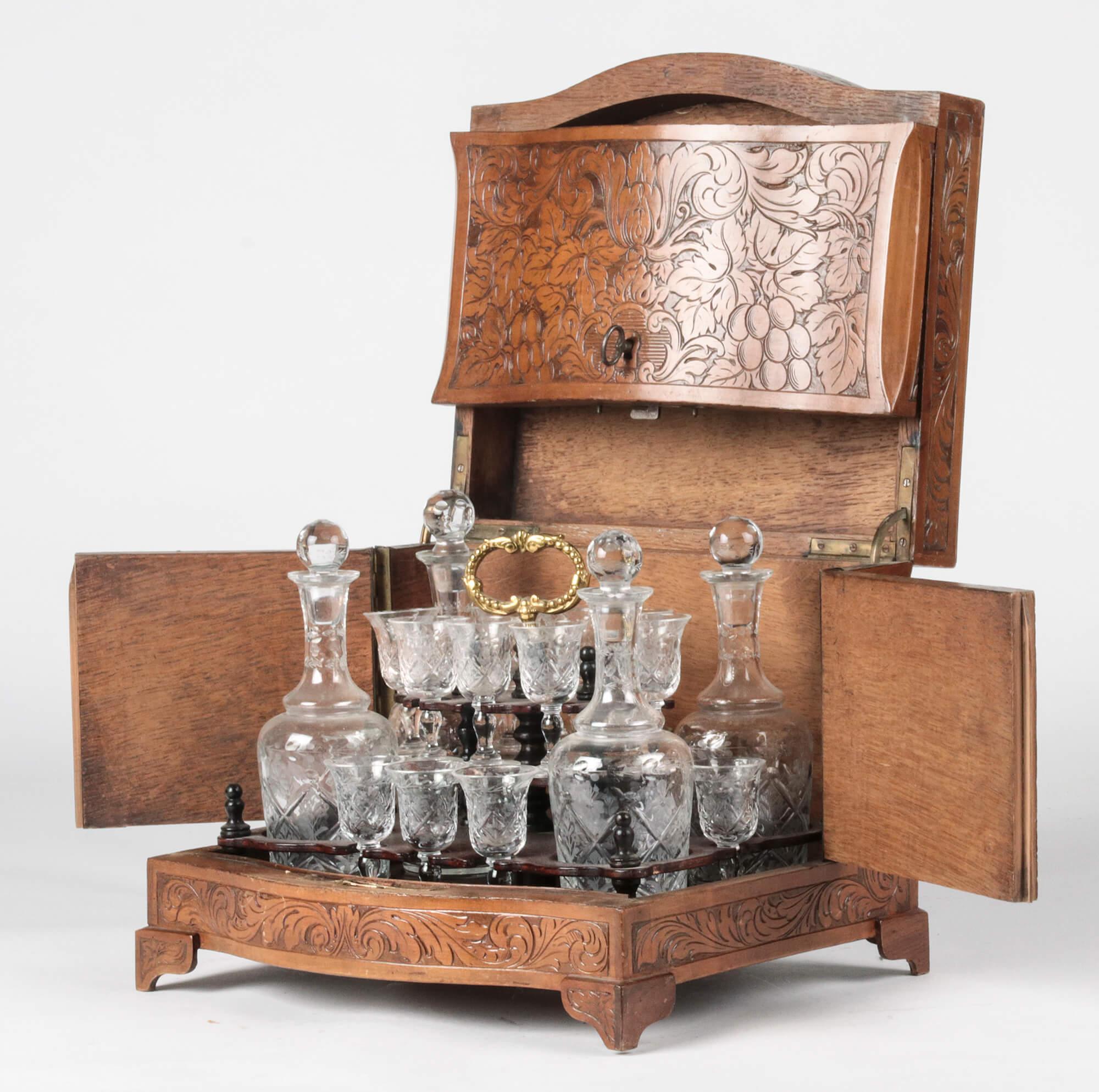 French liqueur set with crystal carafes and glass. The box is made from hand carved walnut on a oak base, in hunting style. On the lid depicting hunting accessories. The crystal service is in good condition and complete. Three of the glasses have