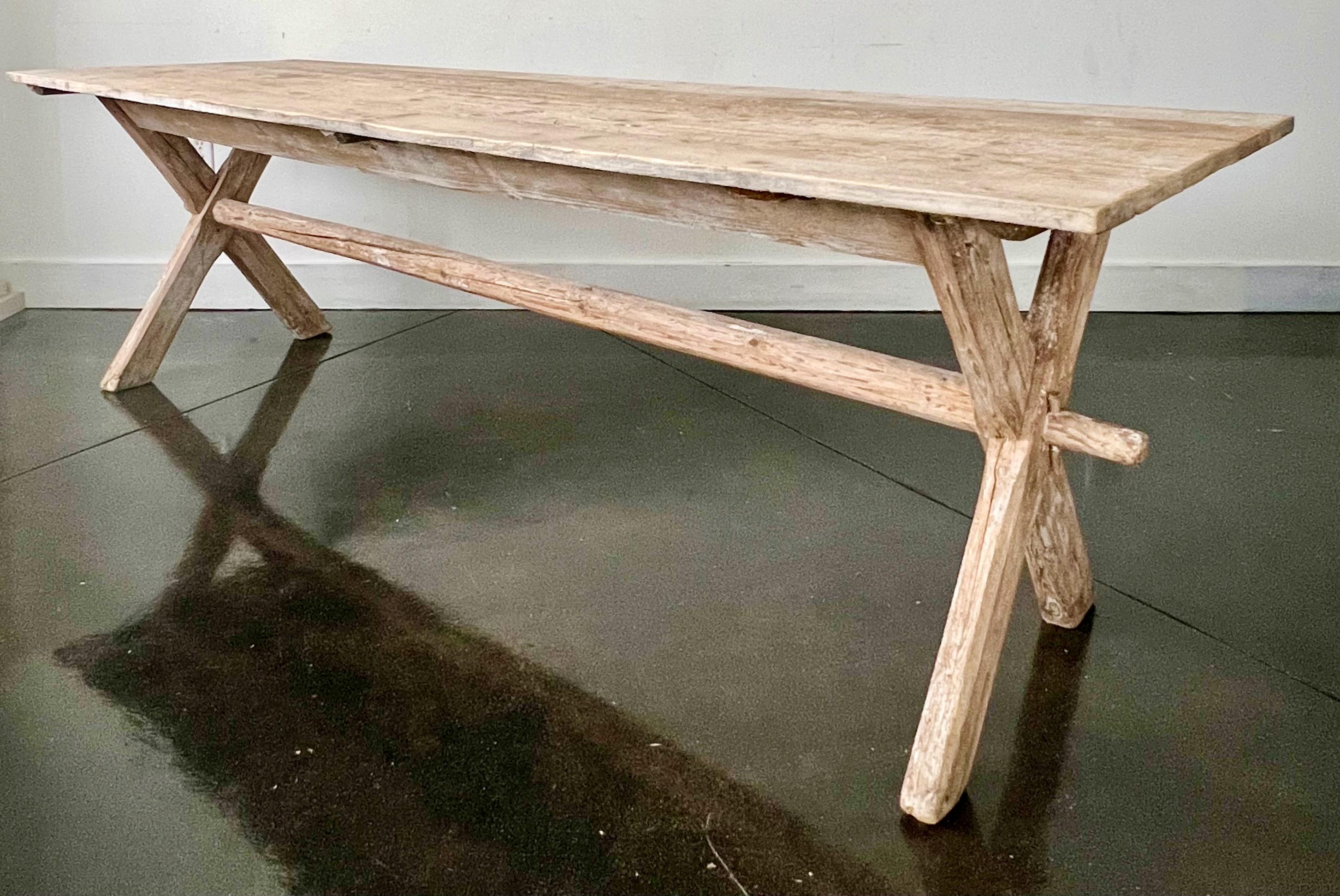 A long 19th century county harvesting table from Alsace, France circa 1840
A rustic harvesting table in worn paint patina and natural pine blanks top on x-shaped base held by stretcher and keyed through-tenons. 
