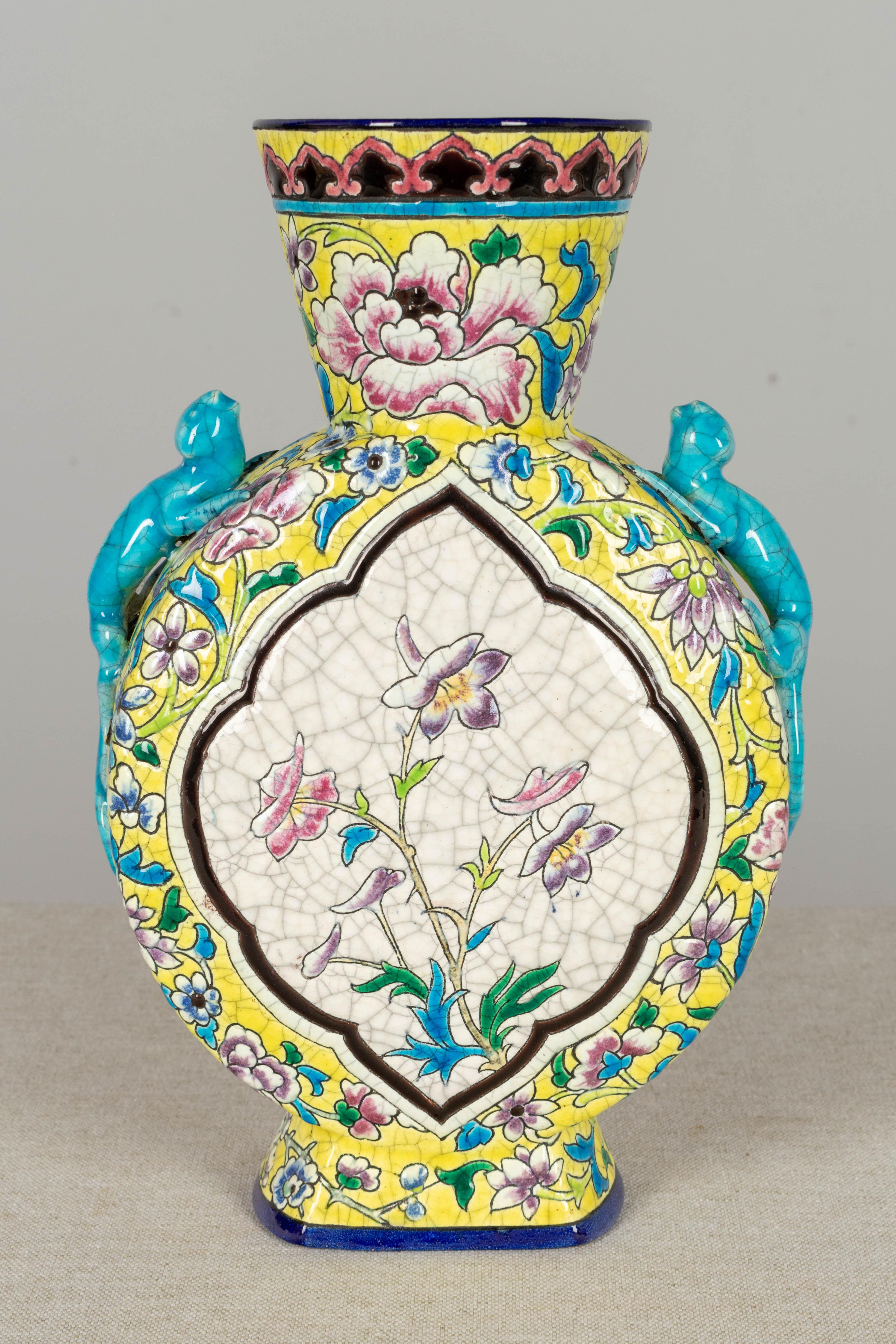 A late 19th century French Longwy chinoiserie ceramic vase, decorated in enamel cloisonné style. Flask shape with bright blue lizard form handles and a vignette on either side, one containing a bird perched on a branch and the other with flowers.