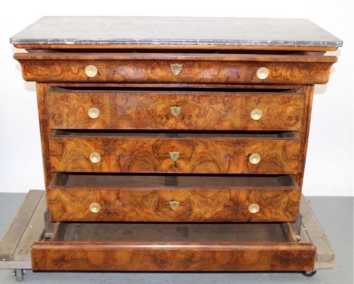 This 19th-century French Louis Philippe burled walnut commode with a marble top is an exquisite piece of antique furniture that embodies the elegance and style of the Louis Philippe period (1830–1848).
The burled walnut veneer gives the piece a