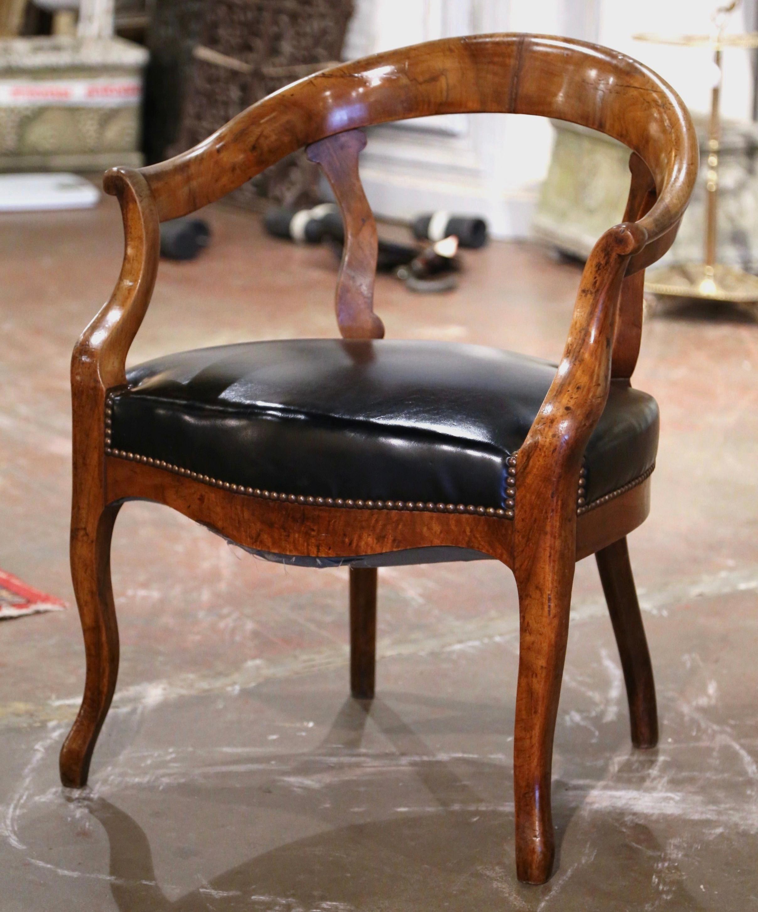 Decorate an office with this elegant antique armchair. Crafted in France, circa 1860 and built of elm, the armchair sits on cabriole legs ending with scrolled feet, over a scalloped and bombe apron. The chair features a rounded and arched back,