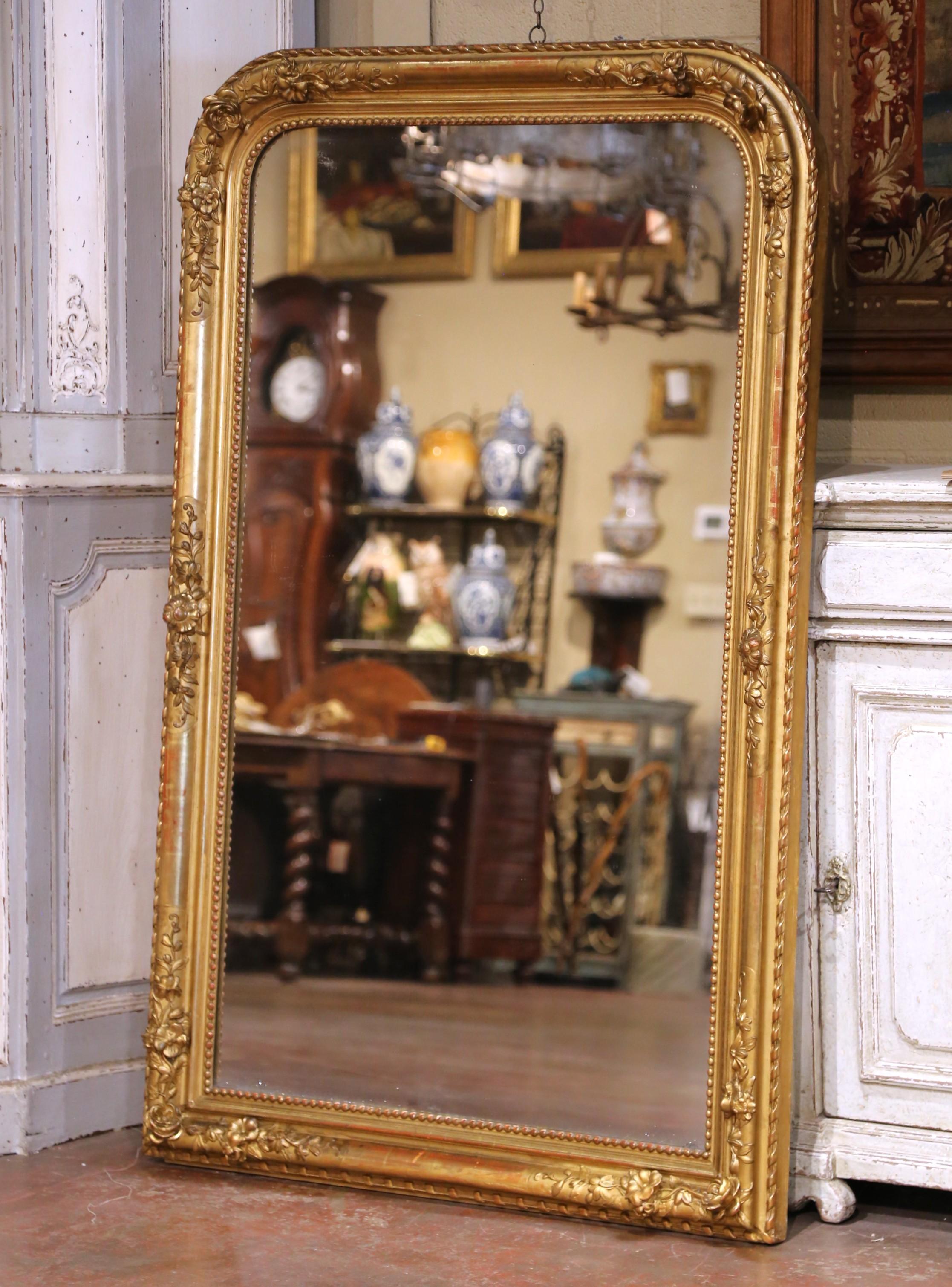 Dieser raffinierte antike Wandspiegel wurde um 1860 in Frankreich hergestellt und weist einen geschnitzten Rahmen aus Goldholz auf, der mit Blumengirlanden und Blattwerk in Hochrelief verziert ist. Die abgerundeten Ecken und der perlenbesetzte