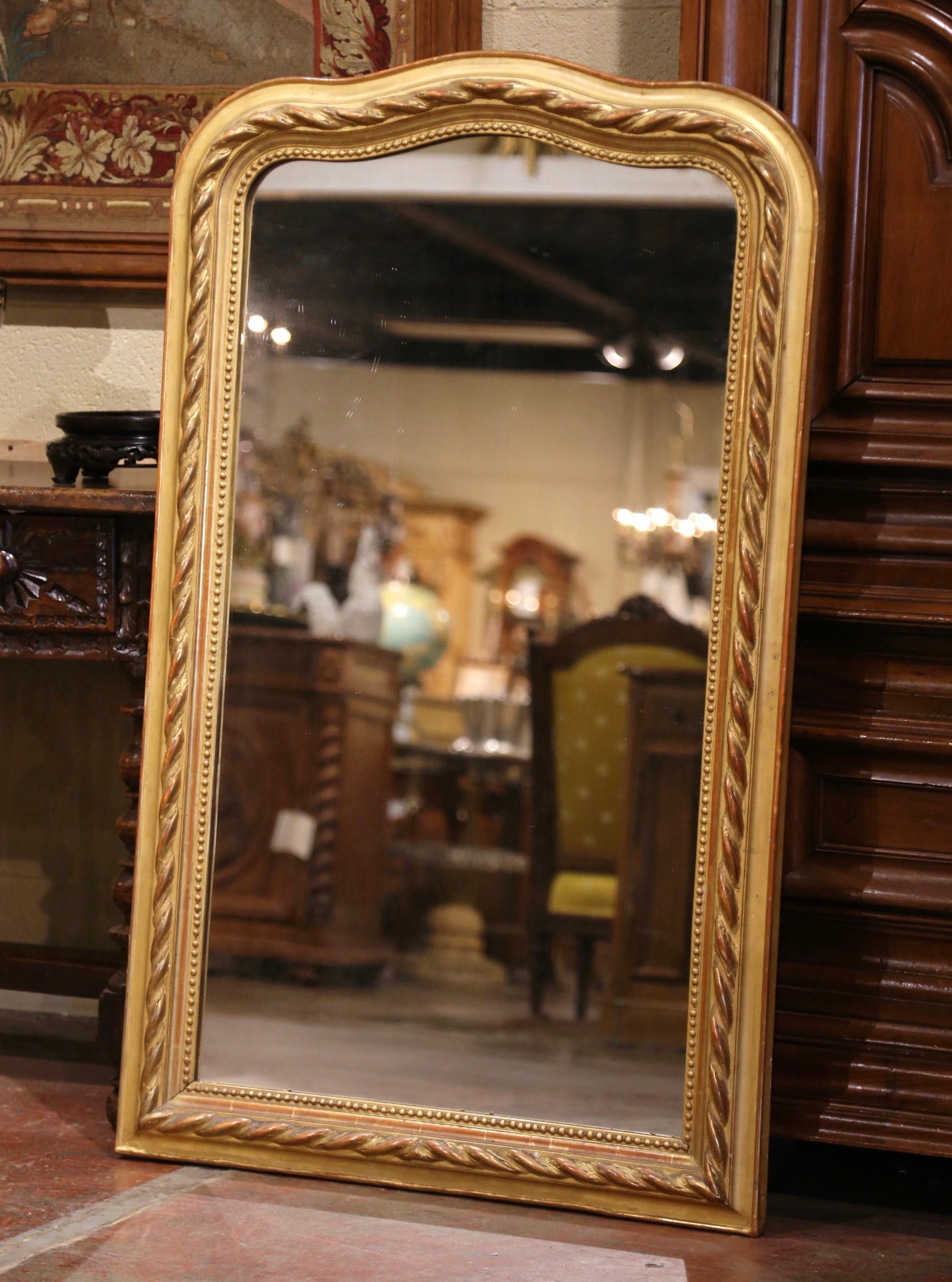 Decorate an entry or a powder room with this elegant antique wall mirror. Crafted in France circa 1860, the tall piece features a beautiful arched top at the pediment. The frame with beaded trim around the mirror, is decorated with a fine raised